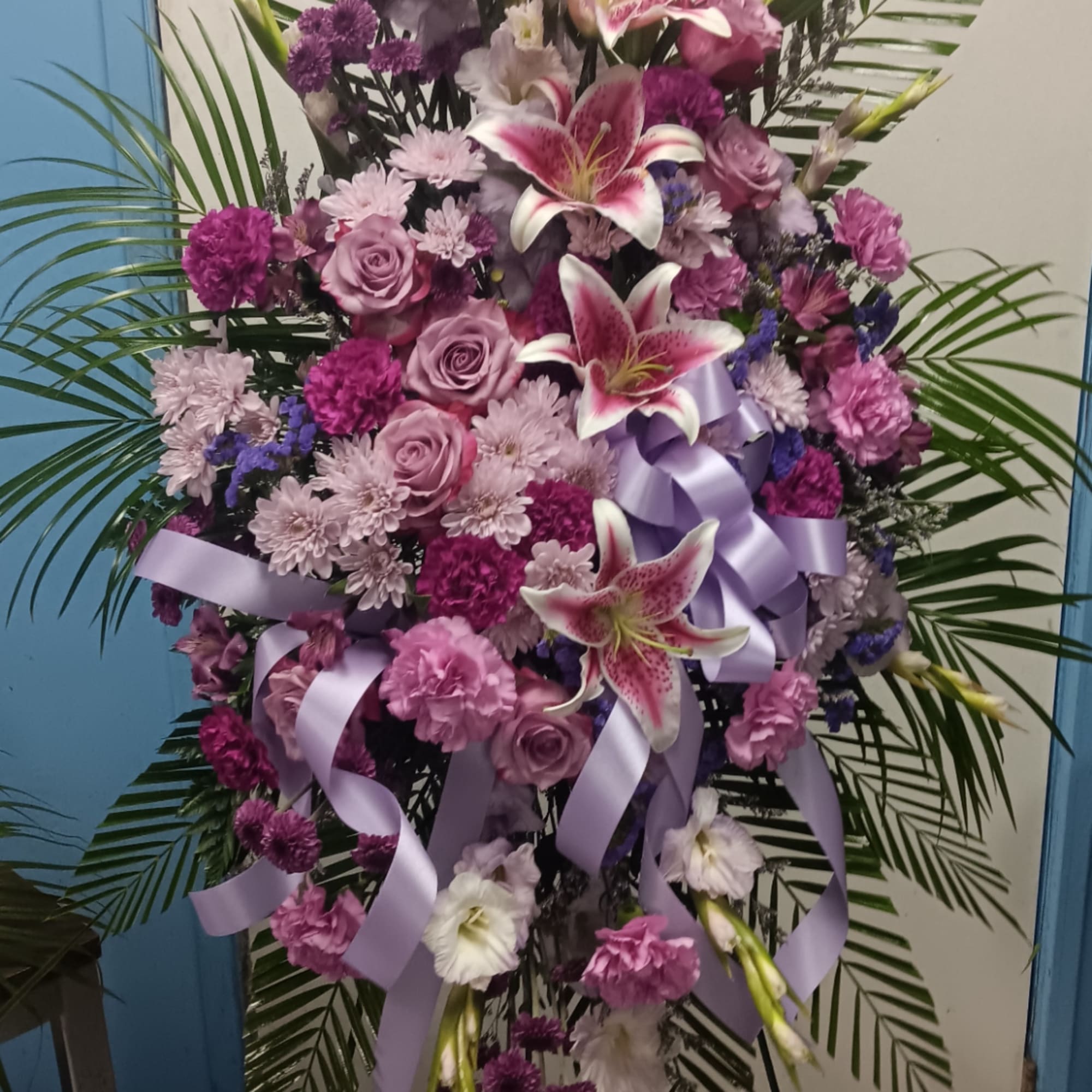 Large purple and pink floral standing spray with lilies and ribbon