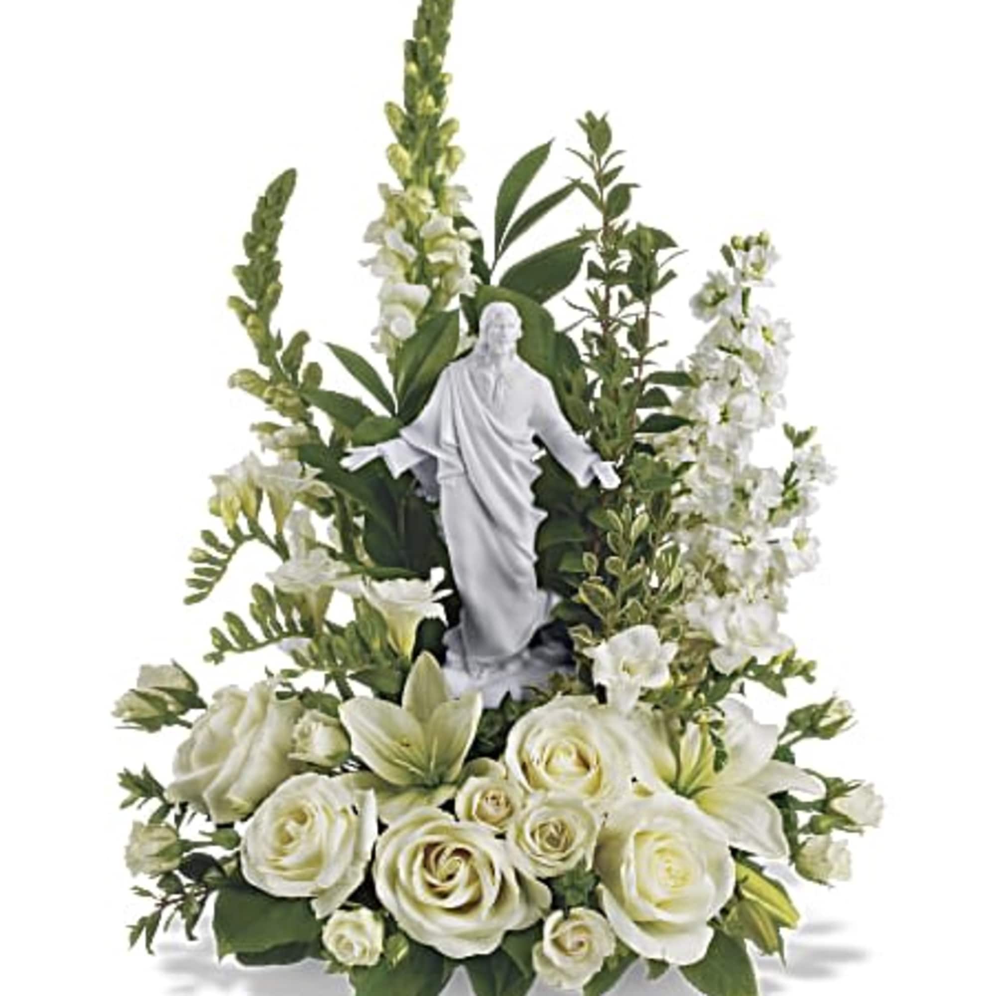 White religious figurine surrounded by white roses, lilies, and tall white flowers in an arrangement