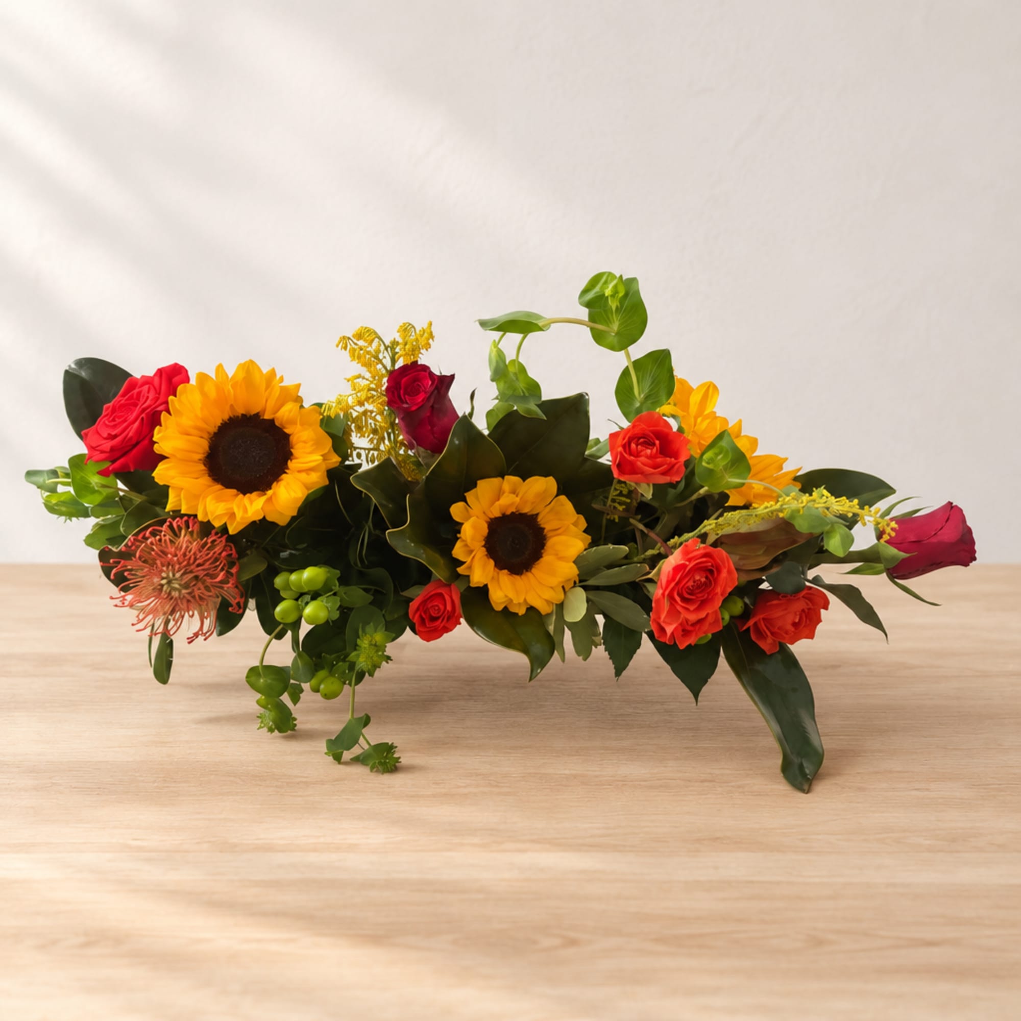 Low floral arrangement with sunflowers and red roses on a table