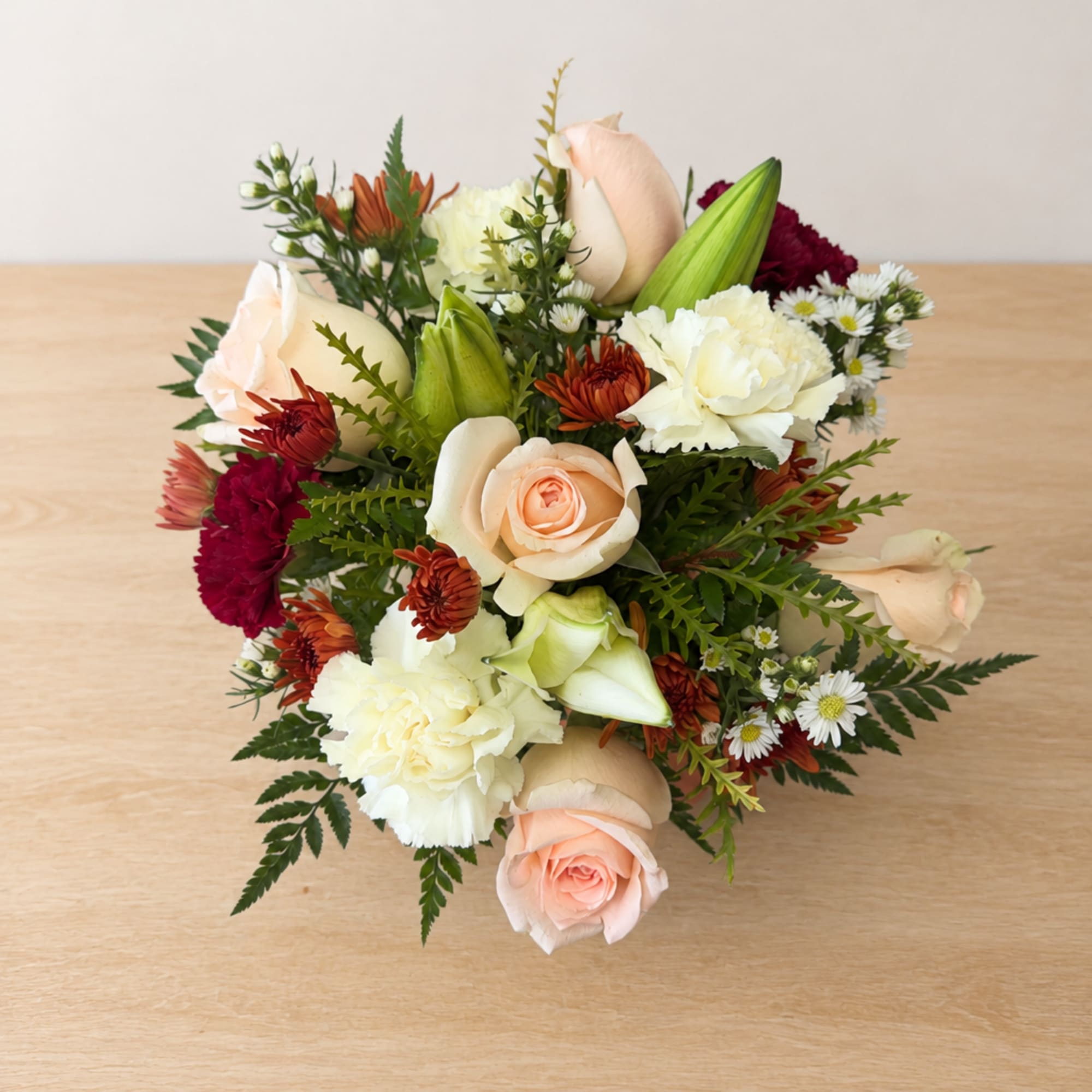 Bouquet of peach roses, white carnations, and mixed daisies on a table