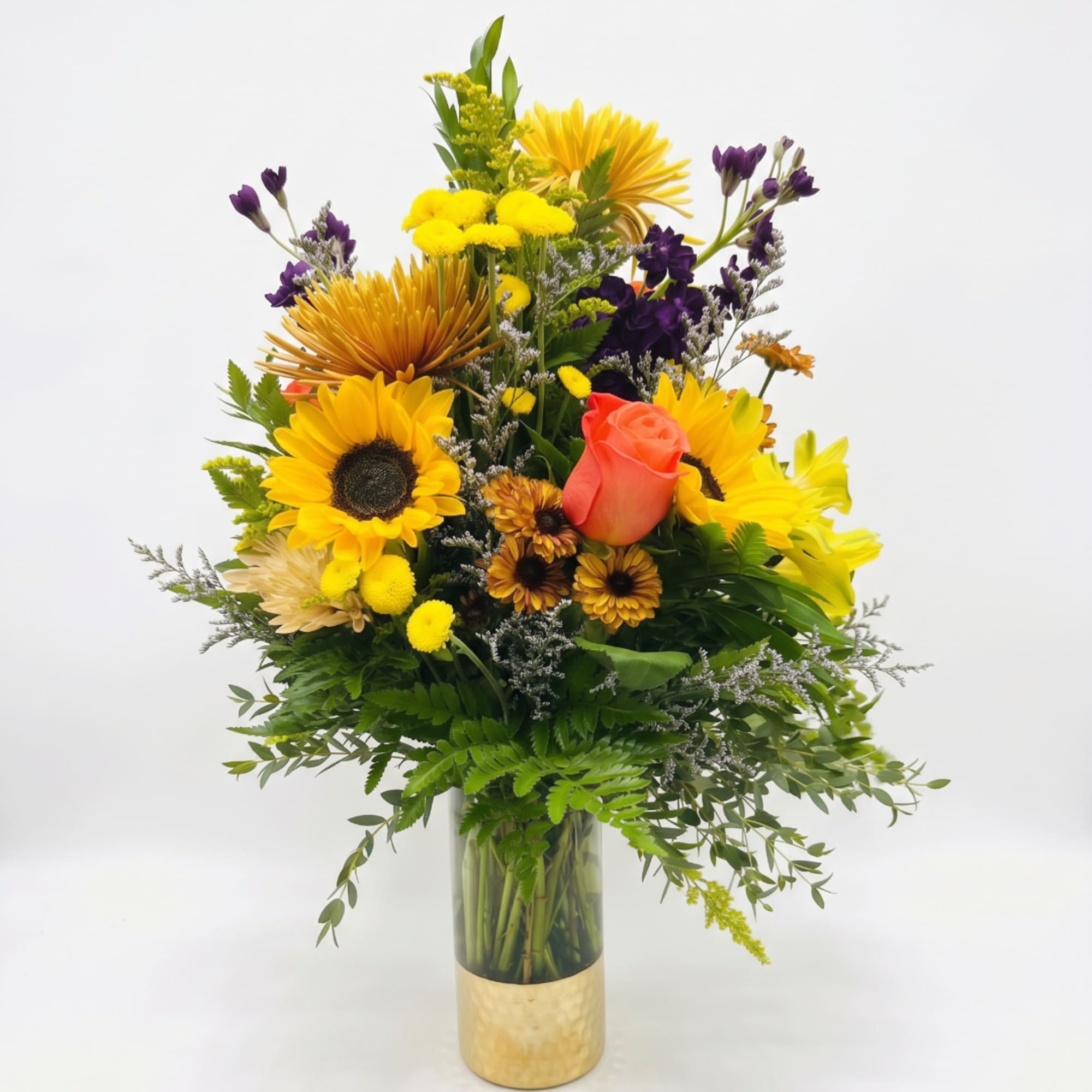 Mixed bouquet of yellow, purple, and coral flowers in a gold vase