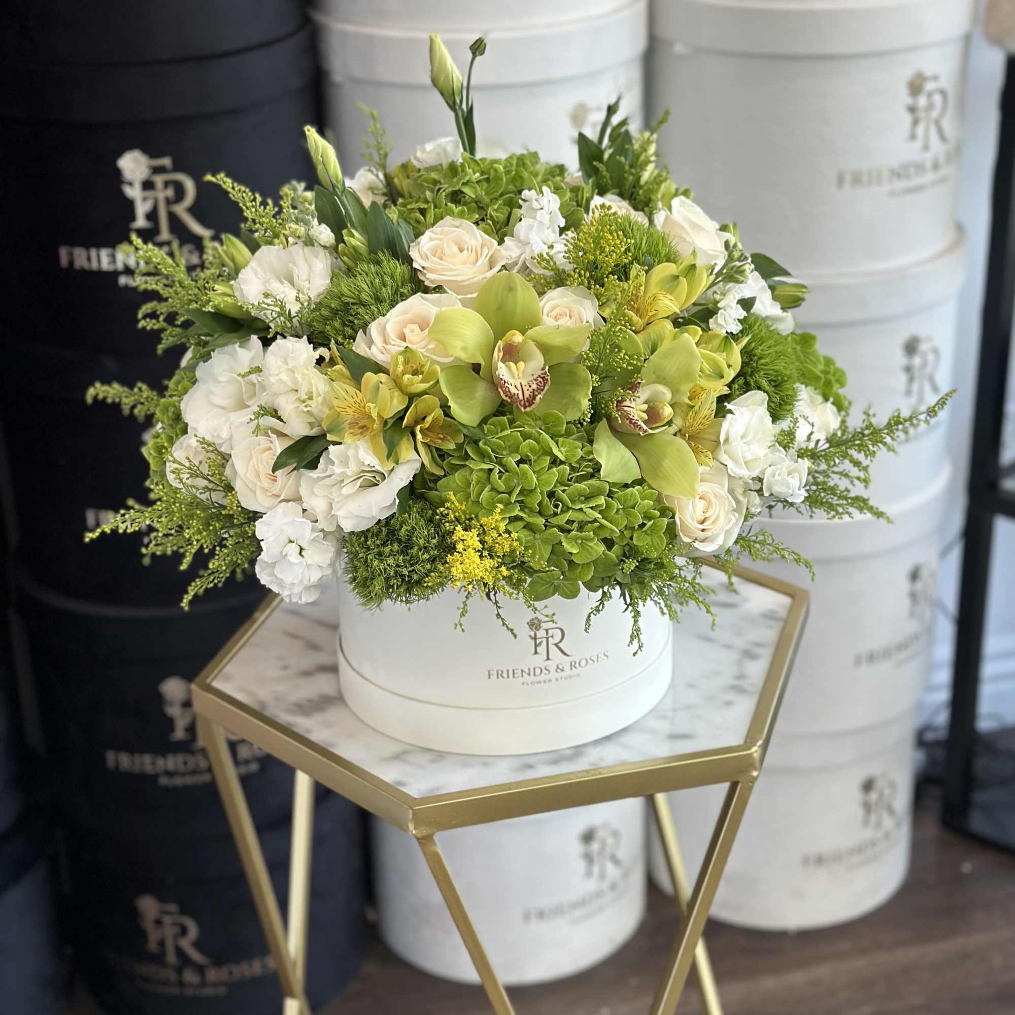 White and green floral arrangement in a round hat box