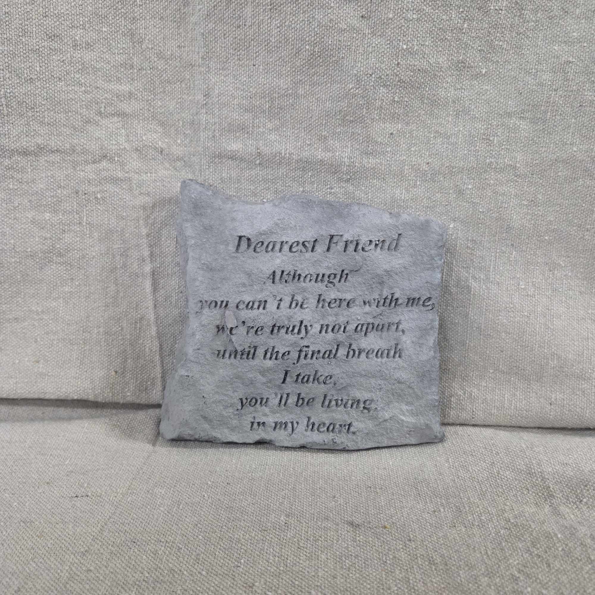 Square gray memorial stone with engraved poem text on a neutral fabric background