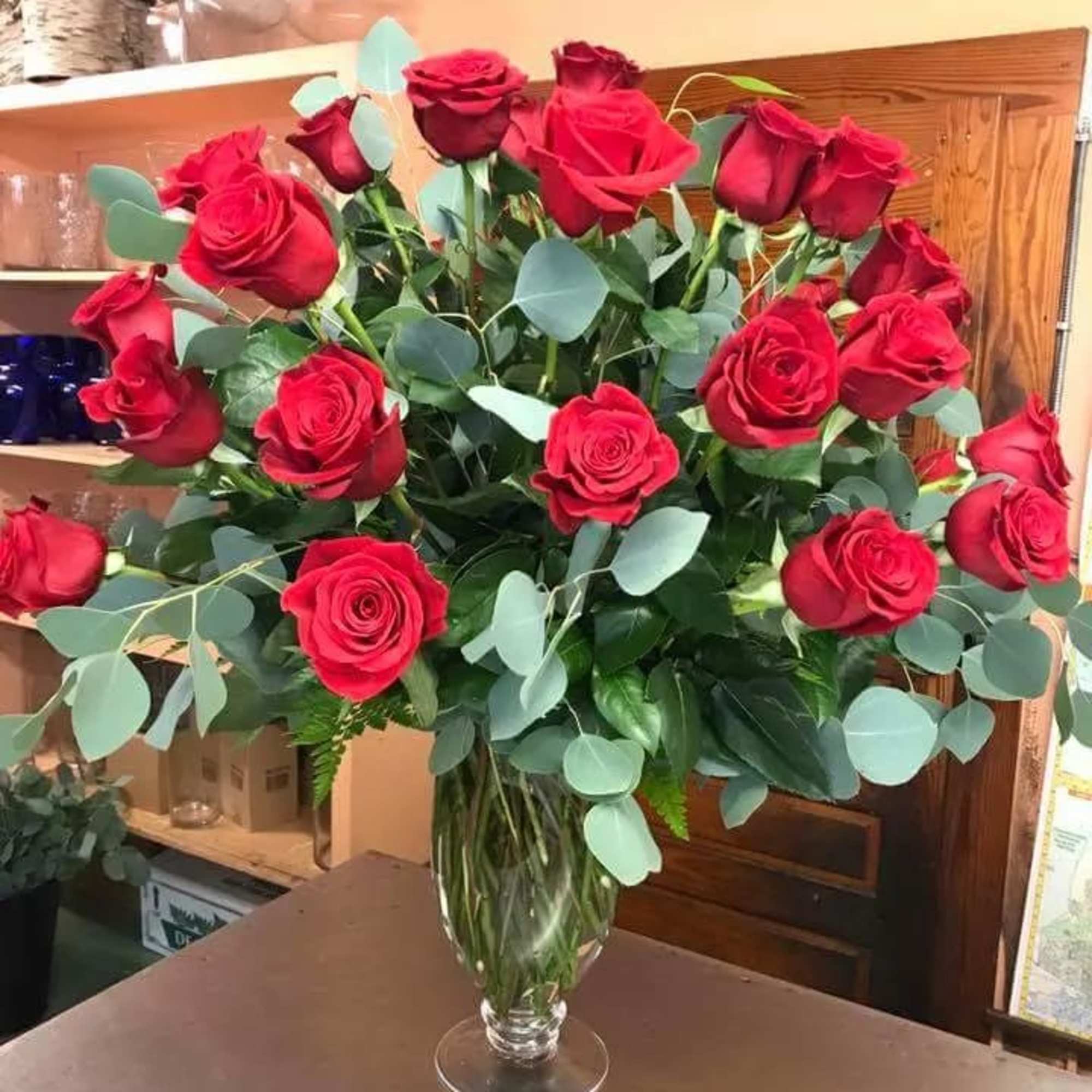 Bouquet of red roses in a clear glass vase with eucalyptus