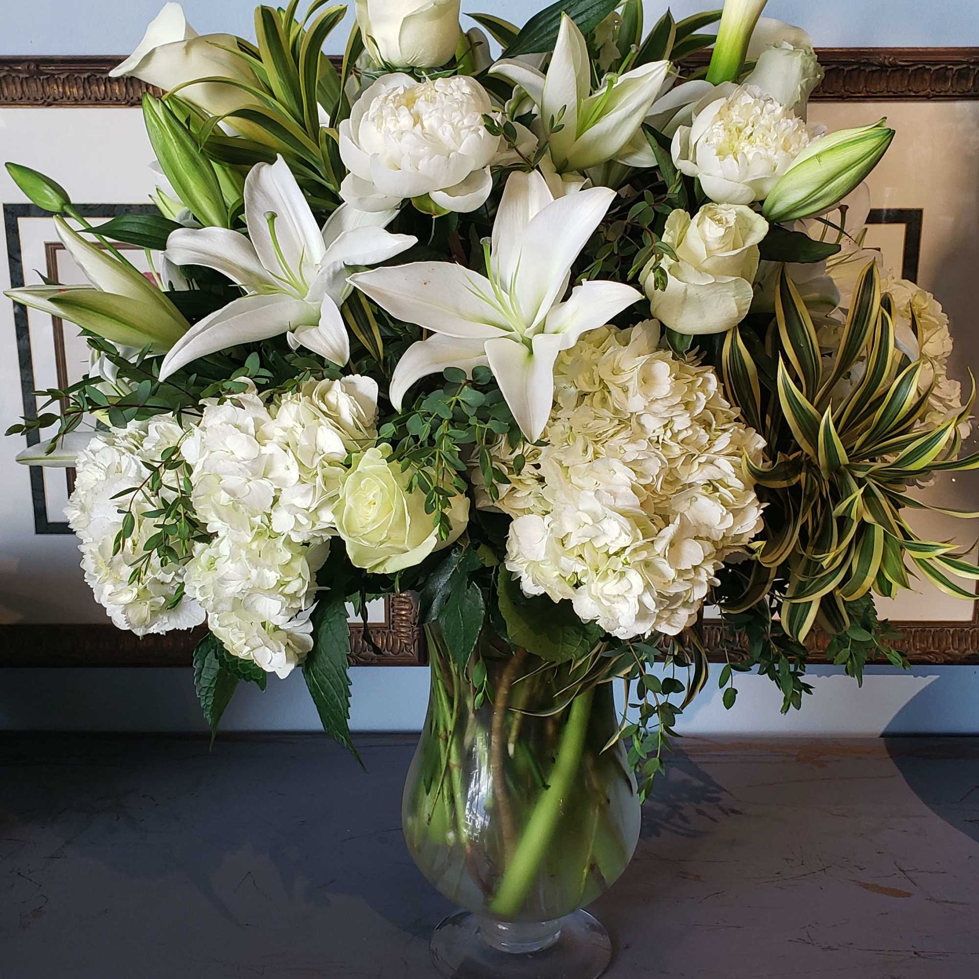 White lilies and roses arranged in a glass vase
