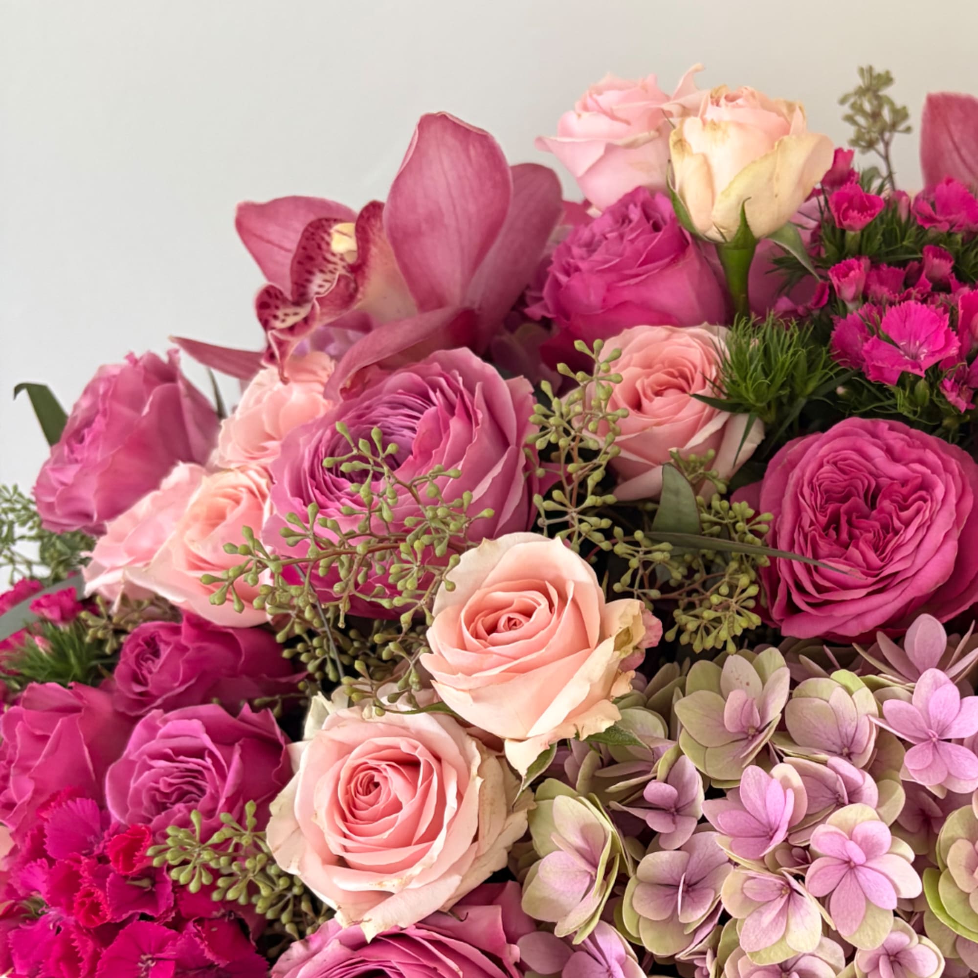 Pink and peach roses with orchids and hydrangea blooms in a bouquet