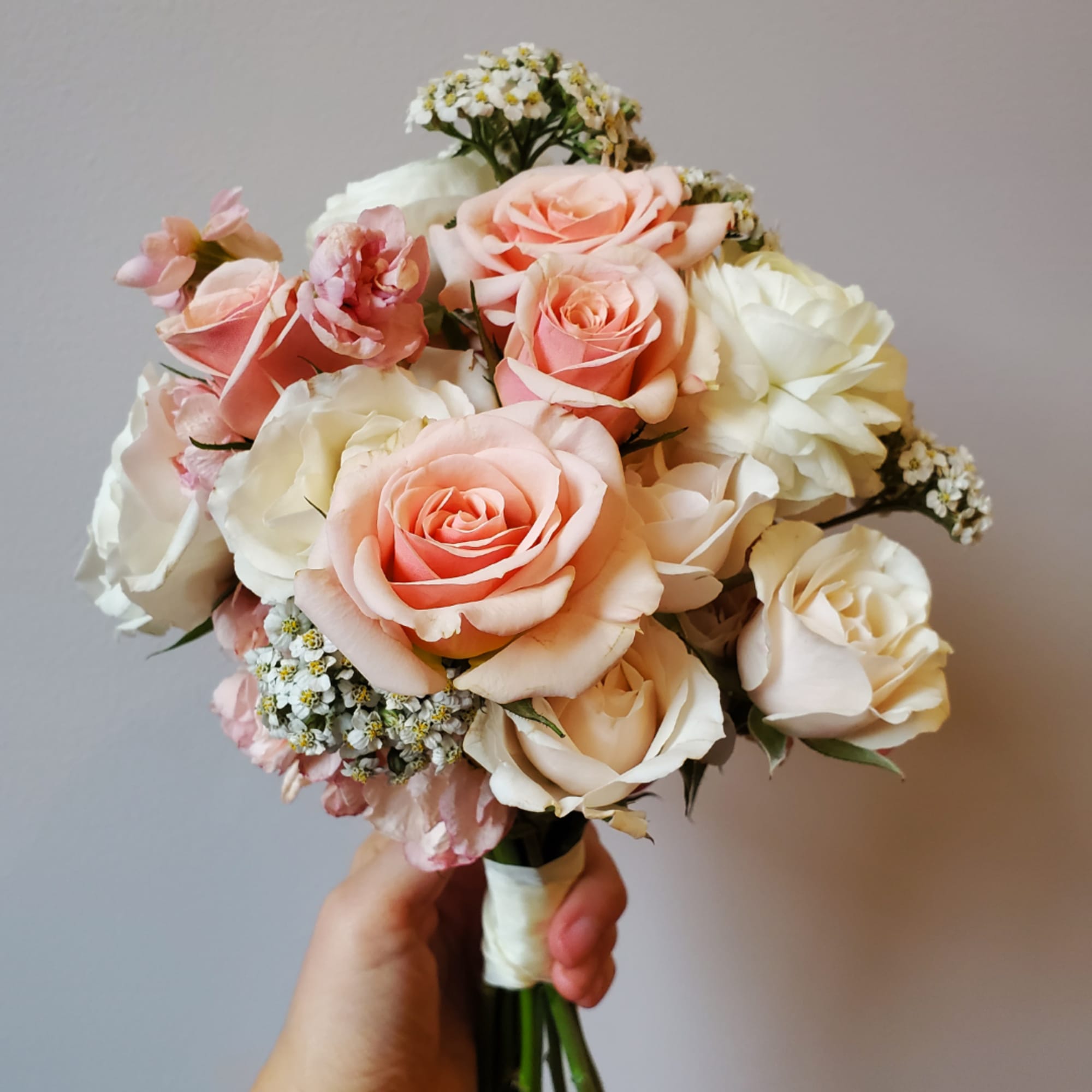 Handheld bouquet of blush and white roses with small filler flowers, photo 2 of 3