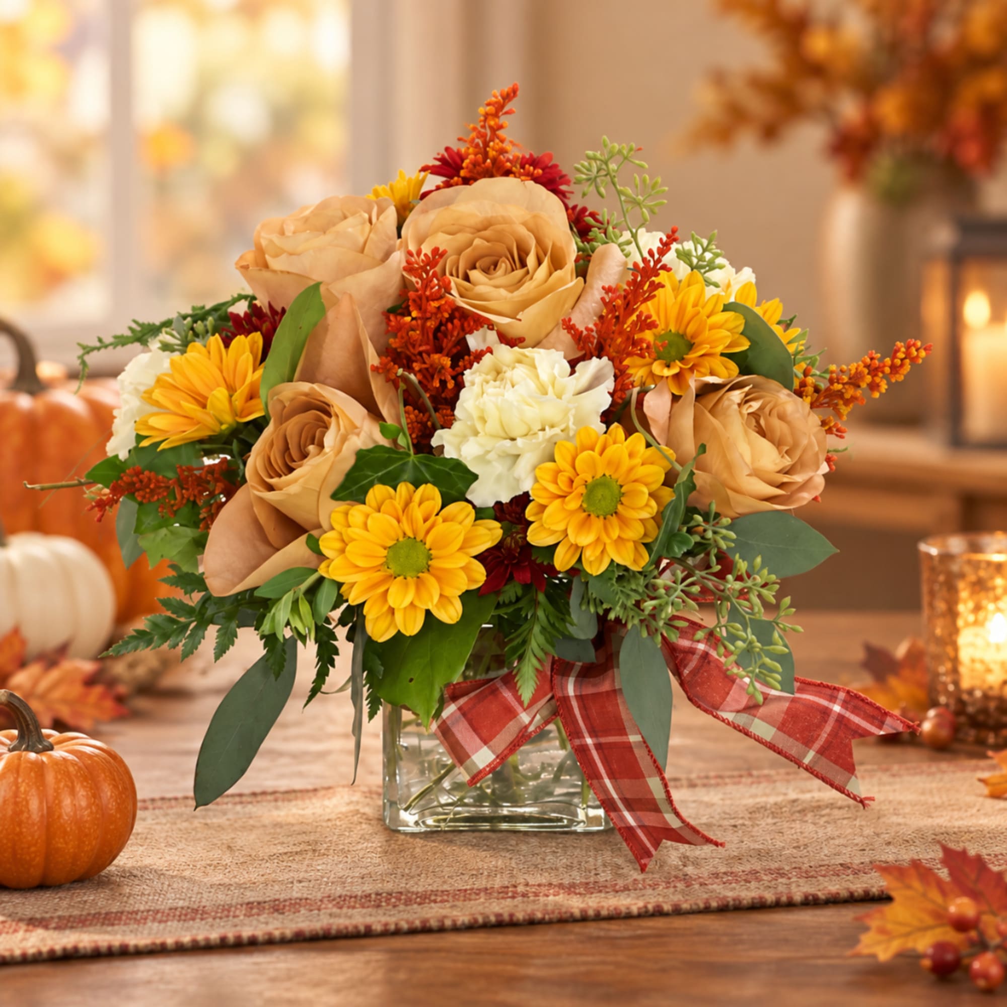 Autumn bouquet of tan roses and yellow daisies in a glass vase