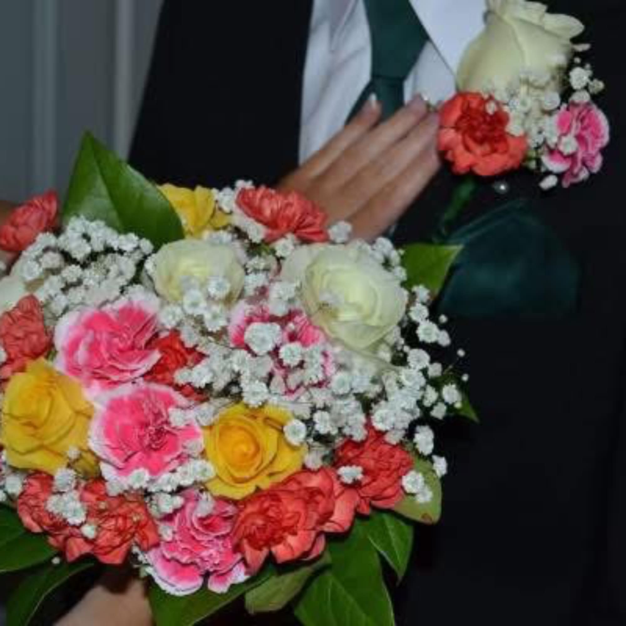 Person holding a colorful bouquet of roses and baby's breath