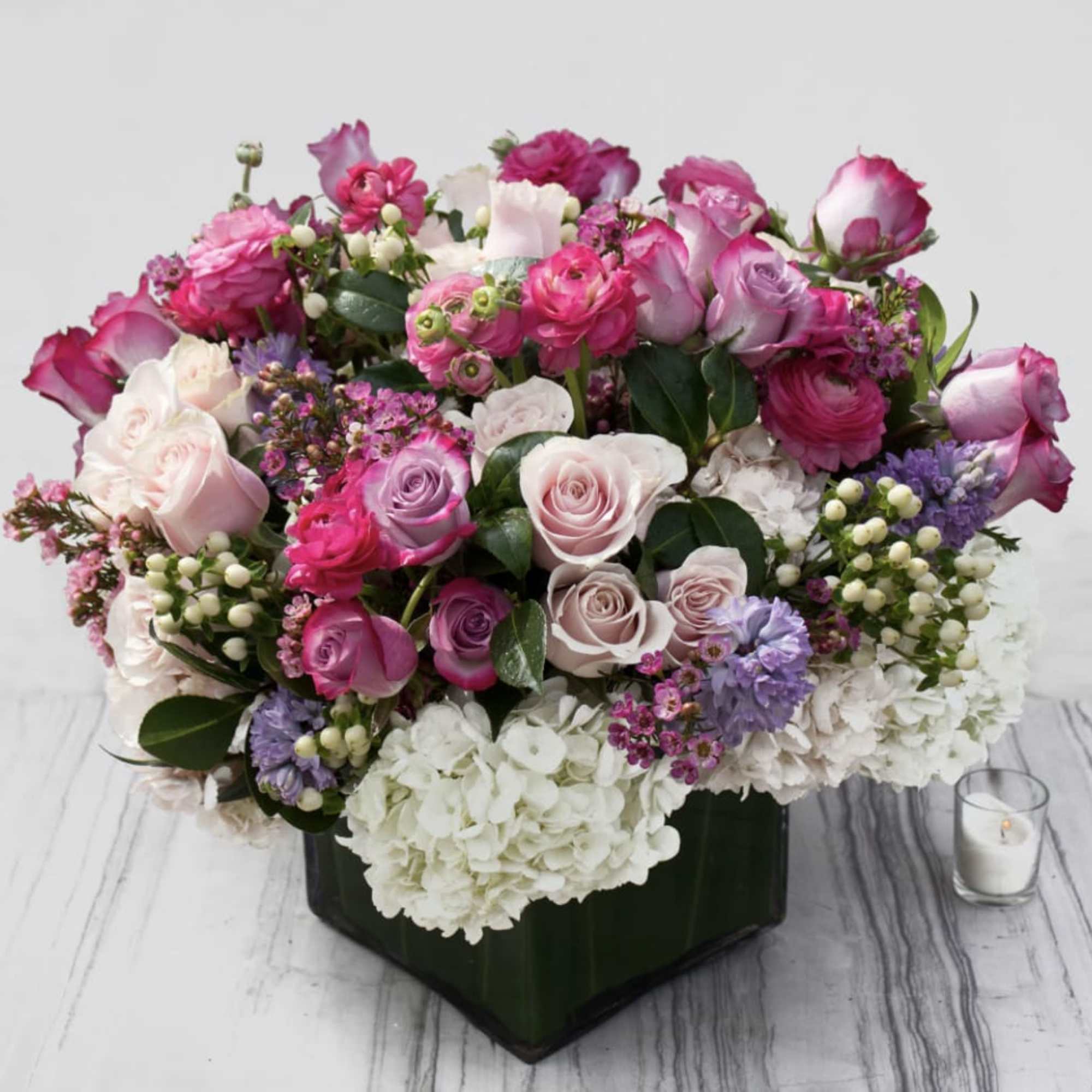 Mixed pink and white flower arrangement in a dark square vase