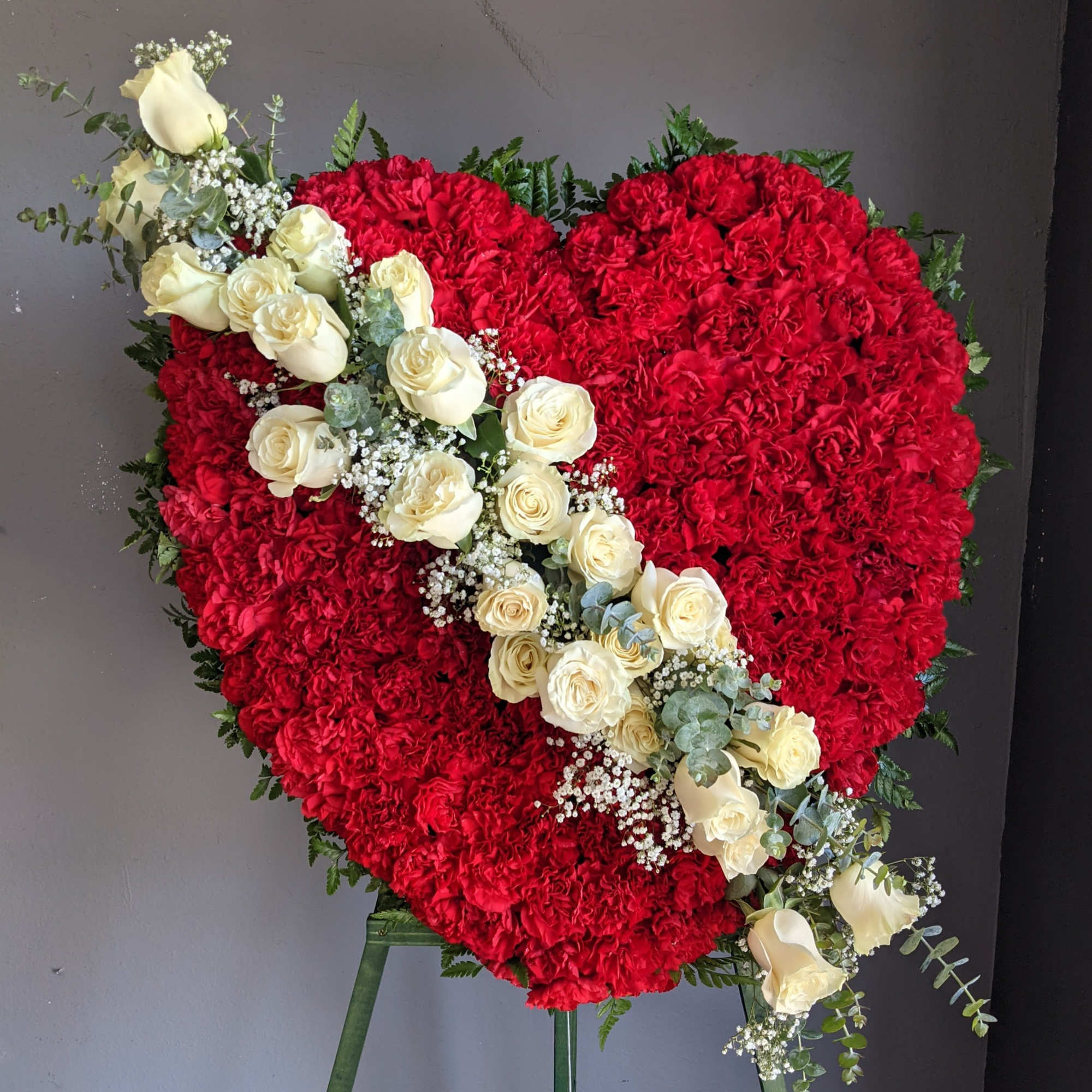 Heart-shaped red floral arrangement with a diagonal spray of white roses