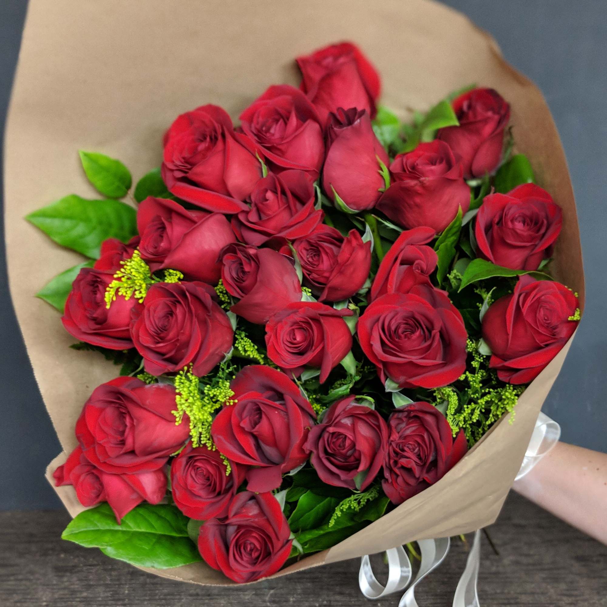 One dozen long stem red roses hand wrapped in brown paper. This