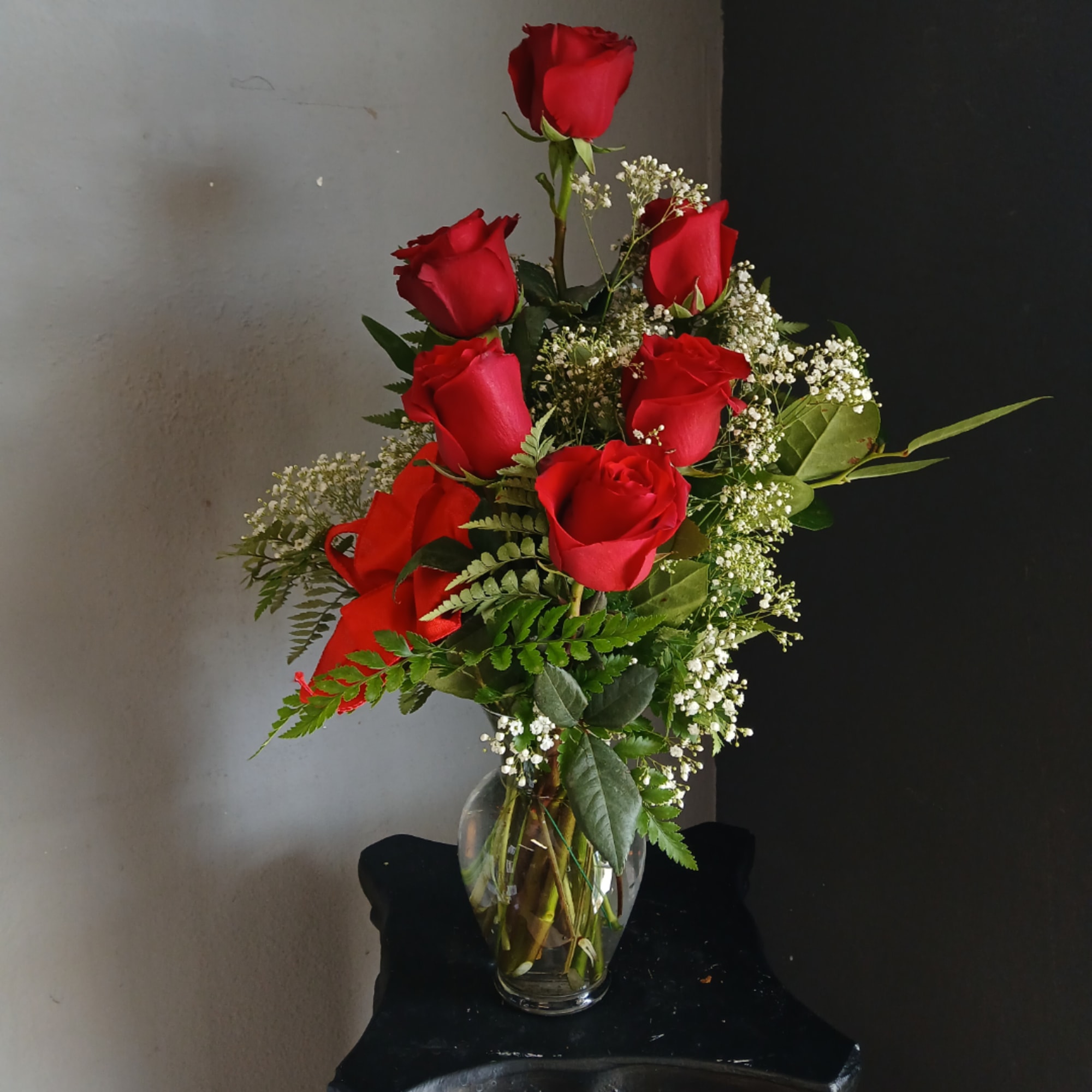 Red roses arranged in a clear glass vase with white filler flowers