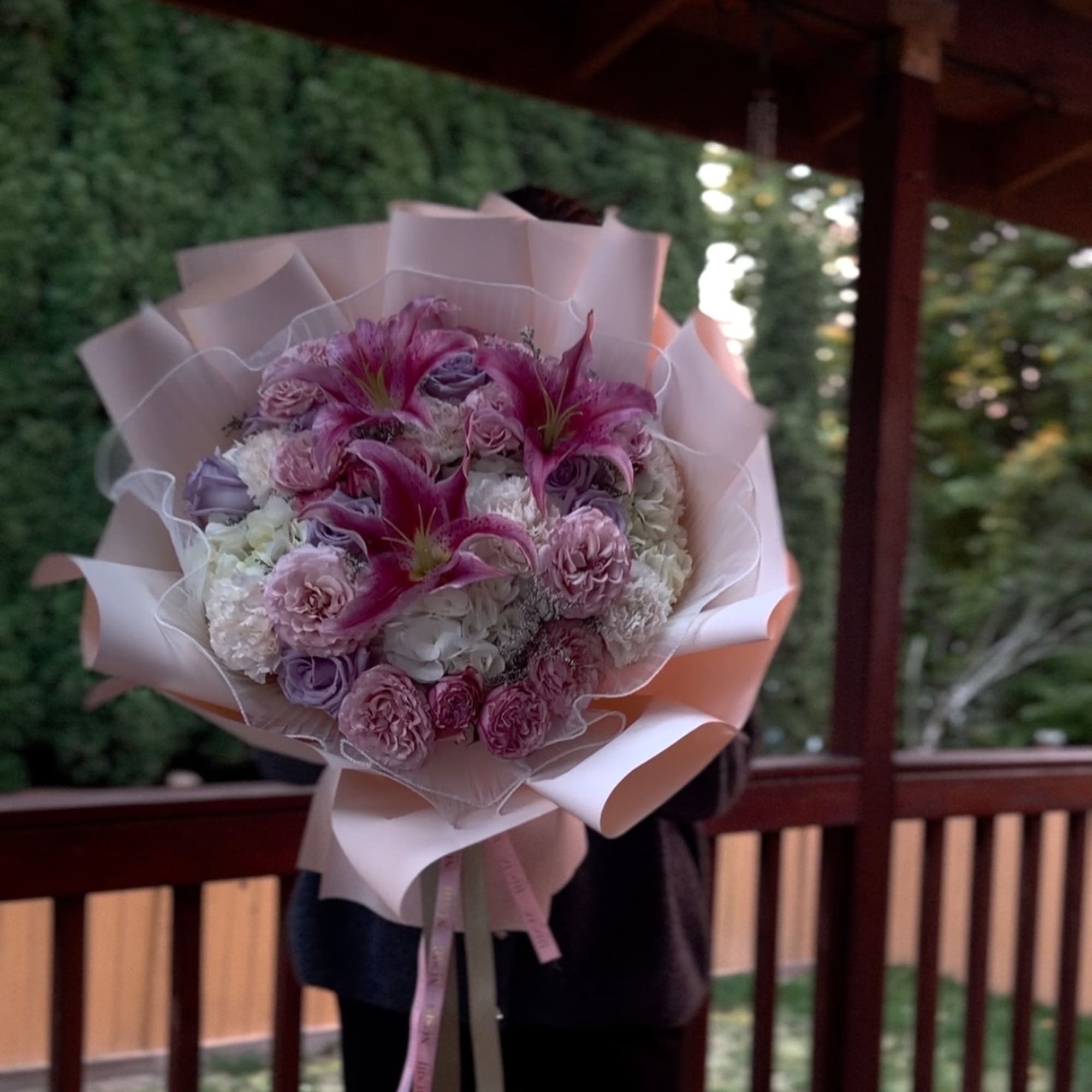 Pink and purple bouquet with lilies and roses wrapped in pale paper