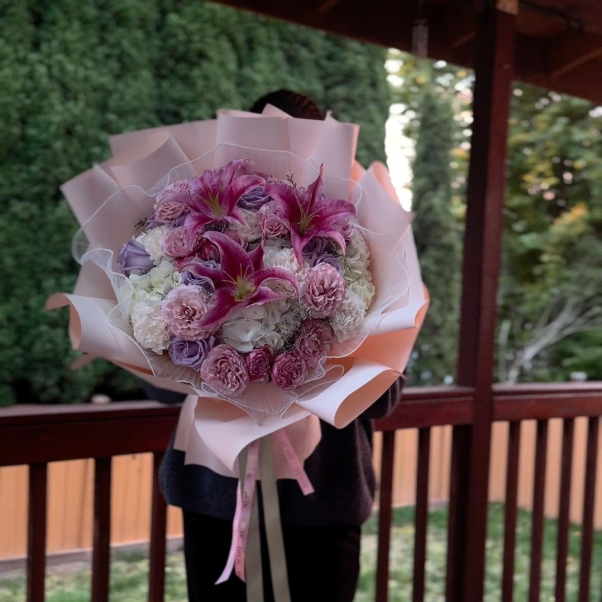 Pink and white bouquet with lilies and roses wrapped in pale paper