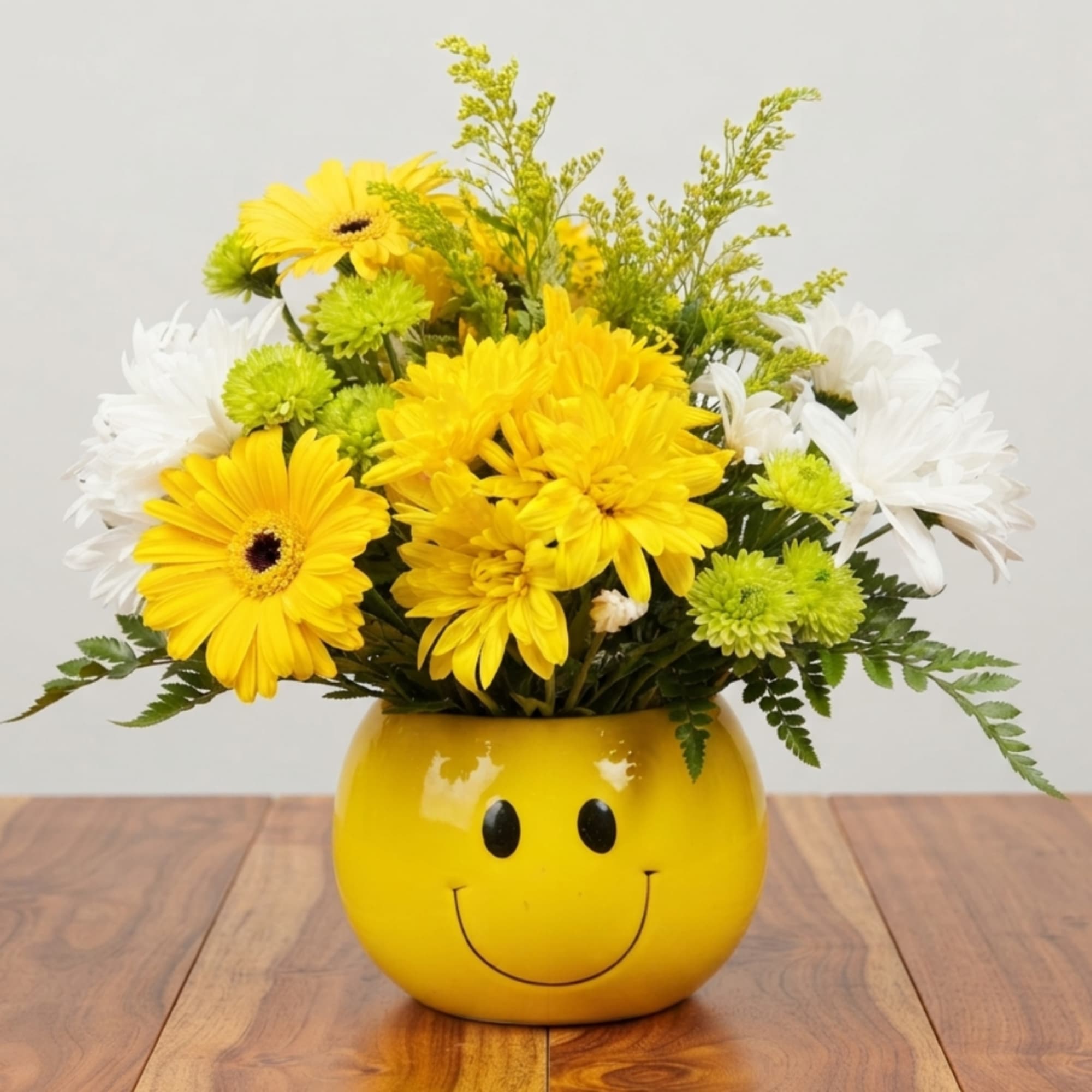 Yellow and white flower arrangement in a smiley-face vase