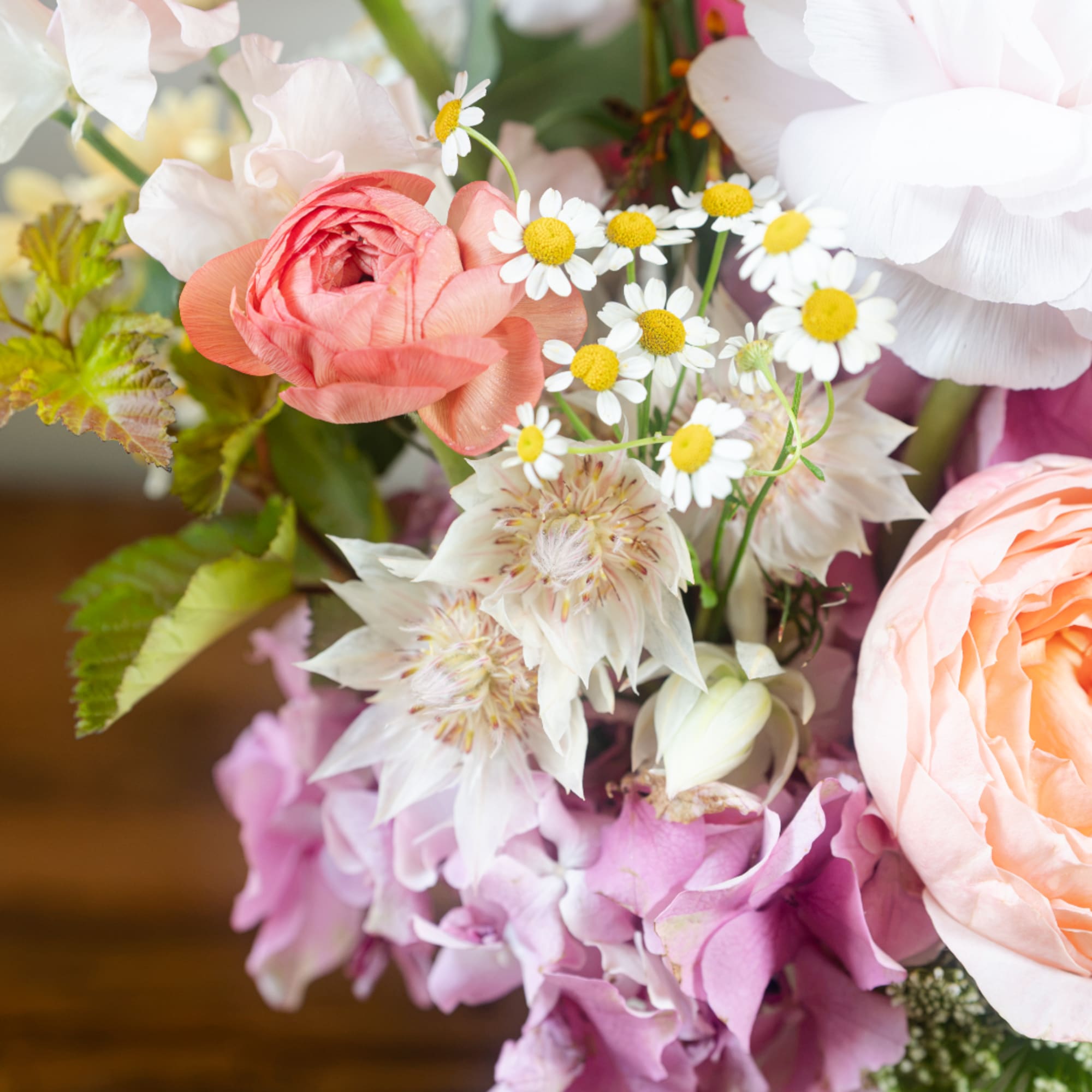 Close-up bouquet with pink and peach blooms and small white daisies