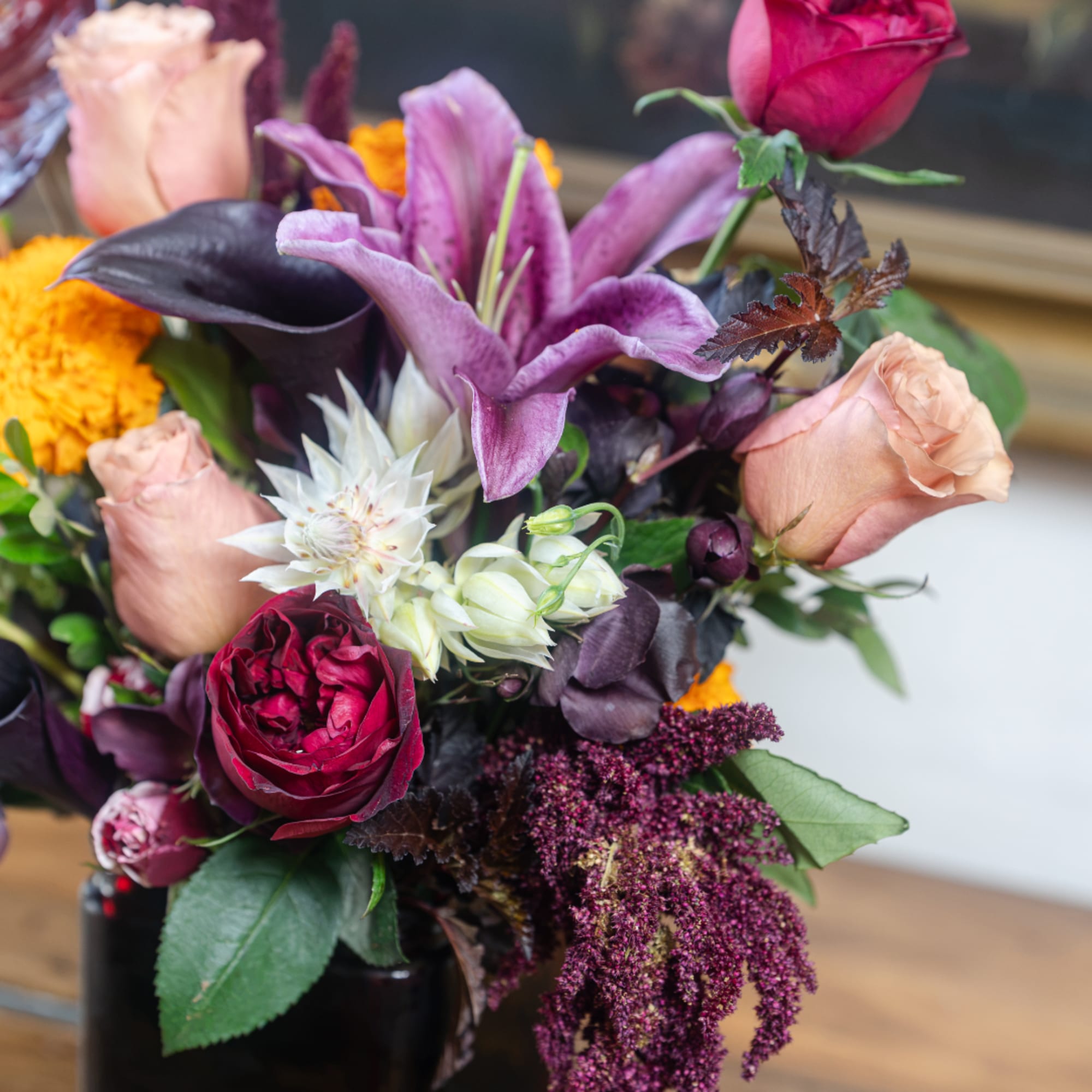 Mixed bouquet with lilies, roses, and dark calla lilies in a vase
