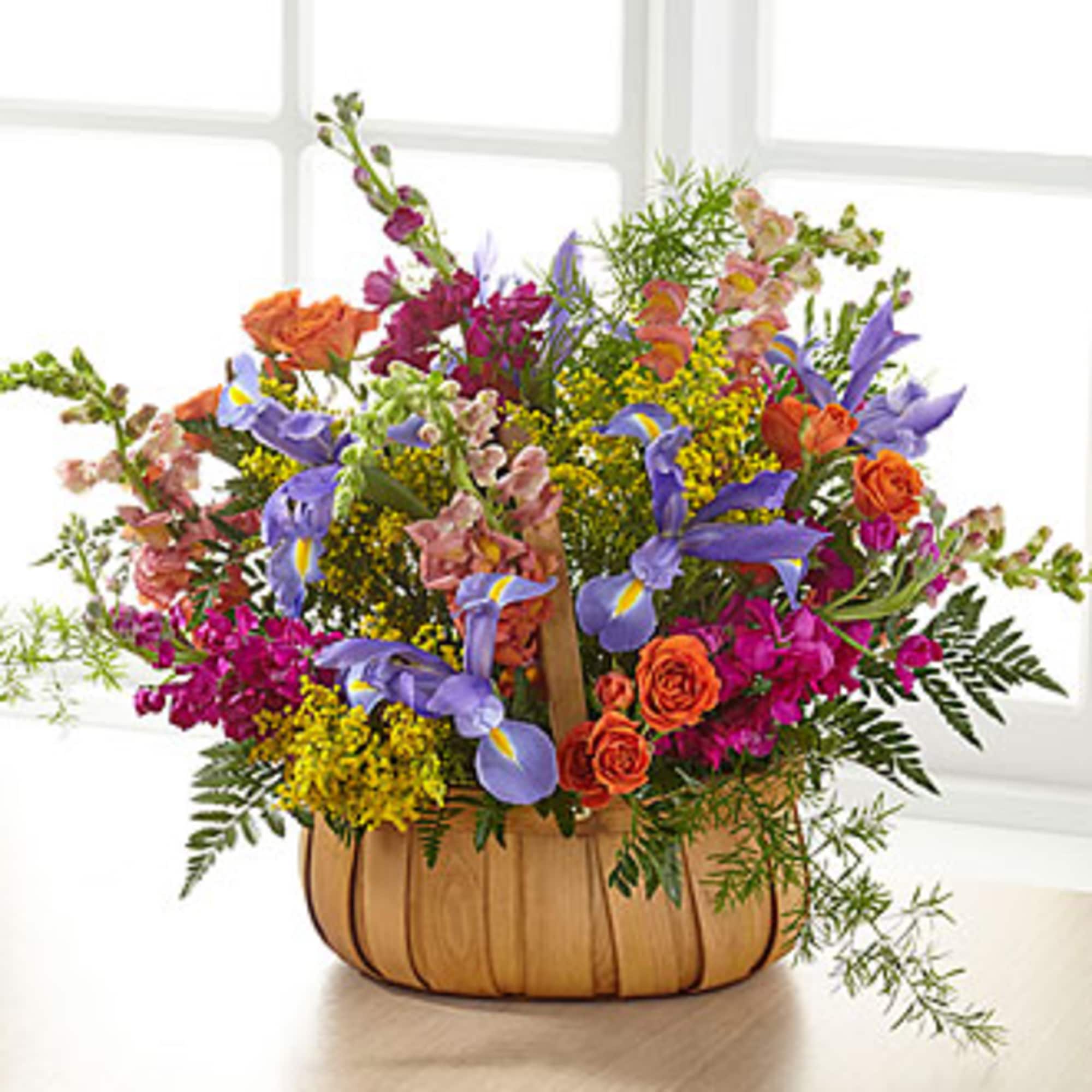 Mixed bouquet in a woven basket with purple irises and orange roses