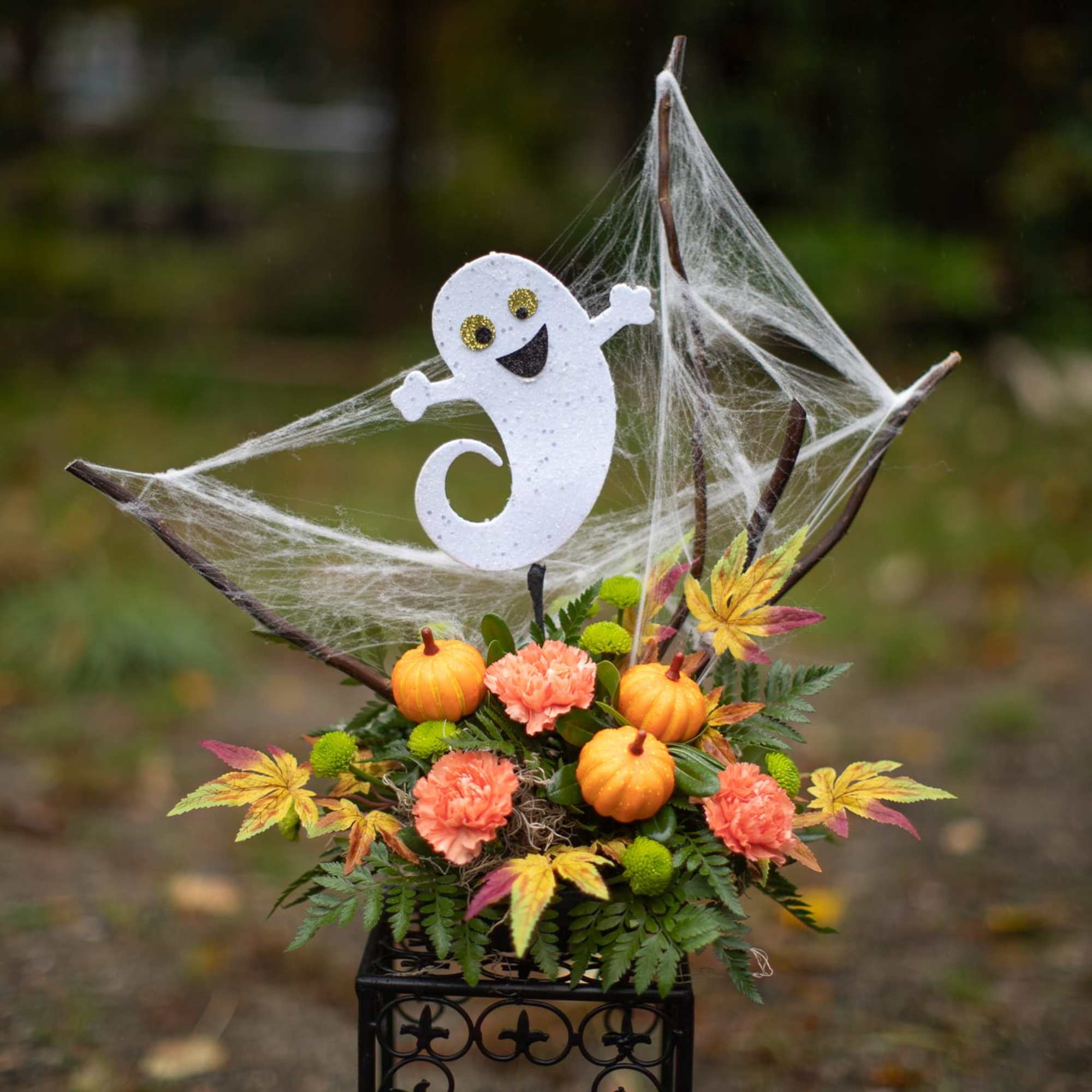 Halloween floral arrangement with pumpkins and a ghost topper