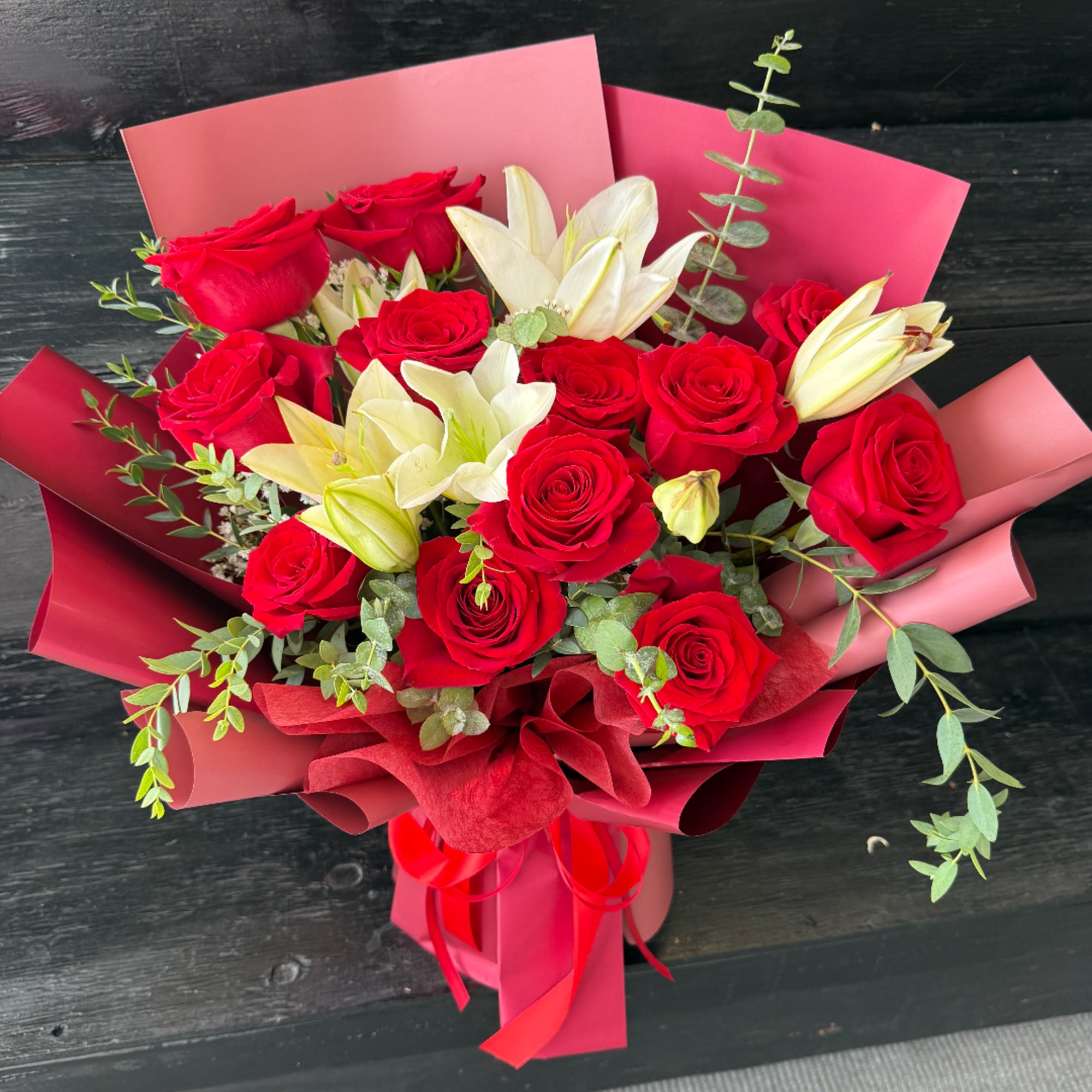 Bouquet of red roses and white lilies wrapped in pink paper