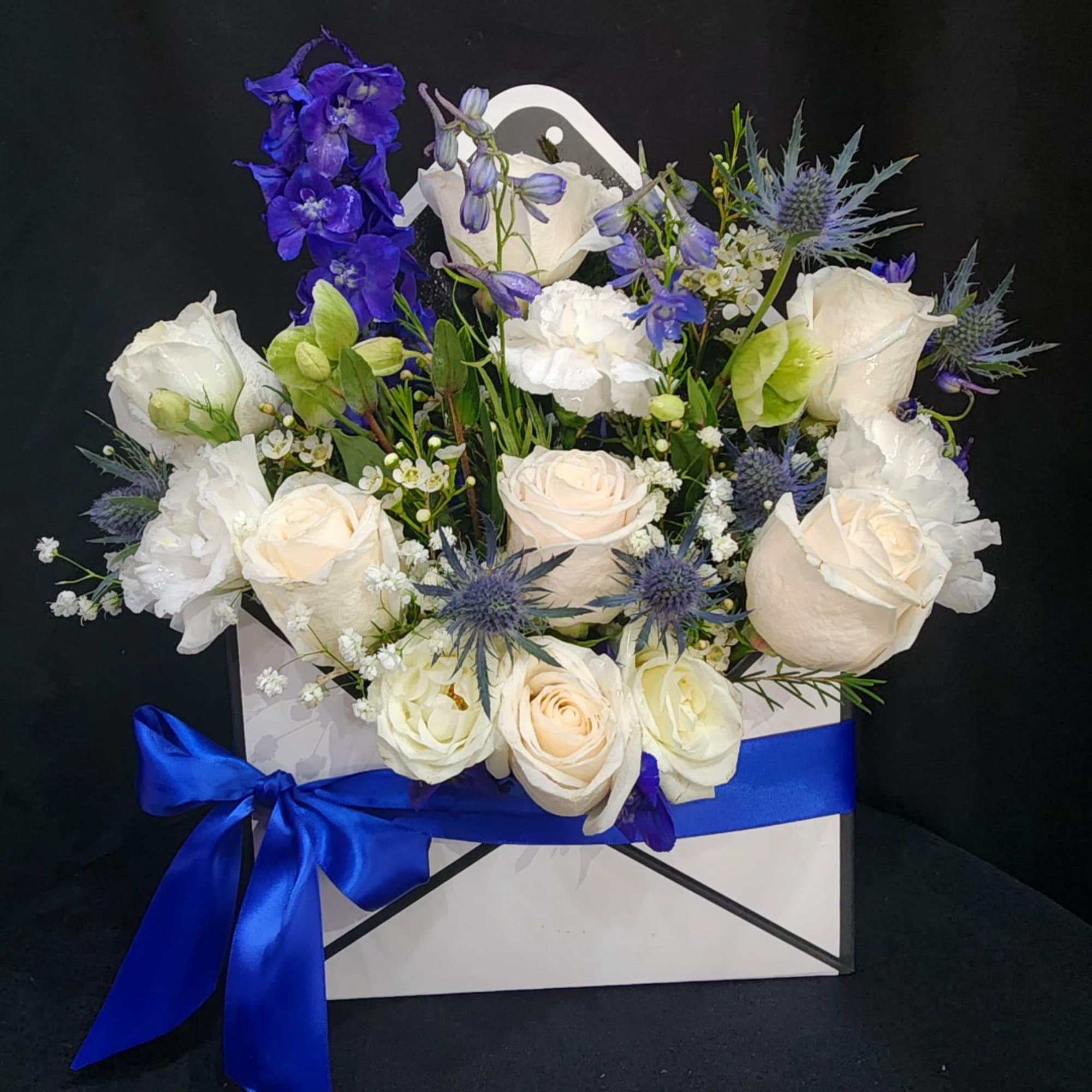 White and blue floral arrangement in a gift box with a satin ribbon