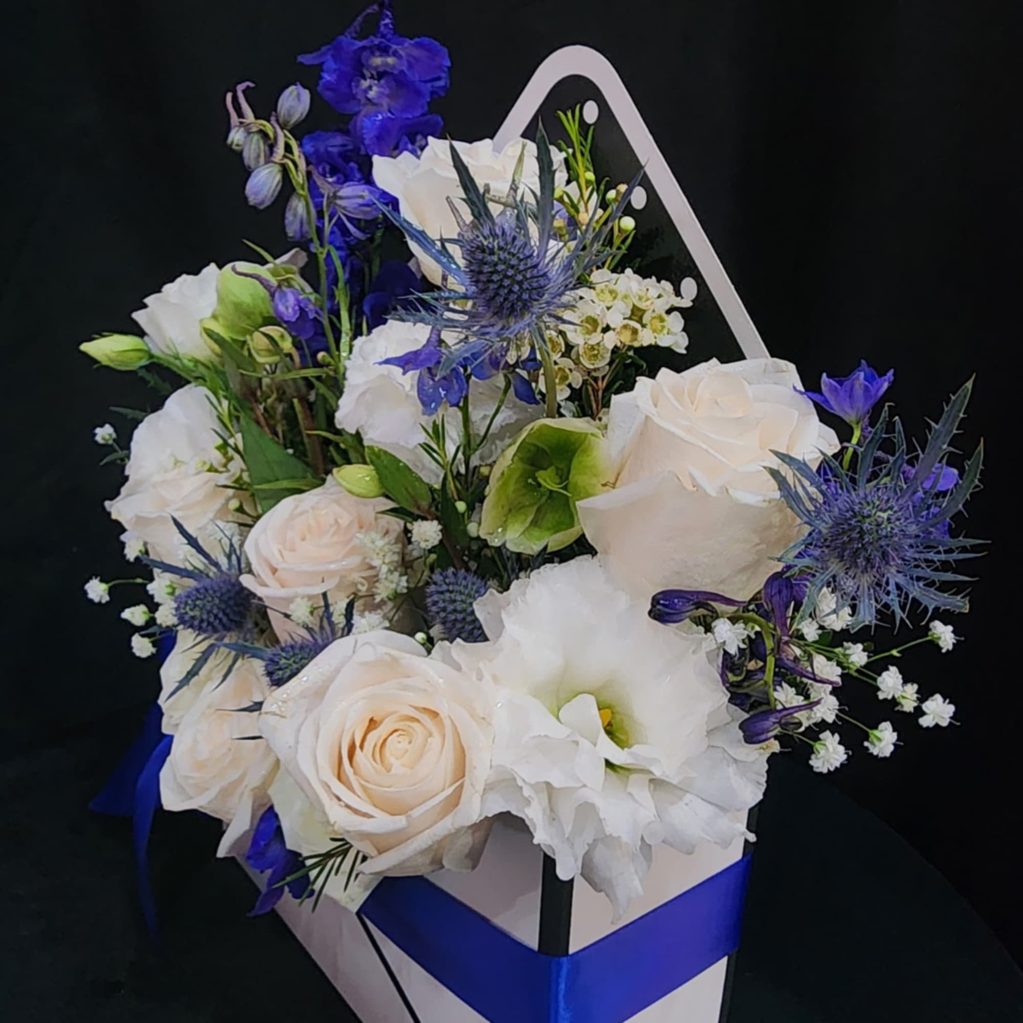White and blue floral arrangement in a gift box with ribbon