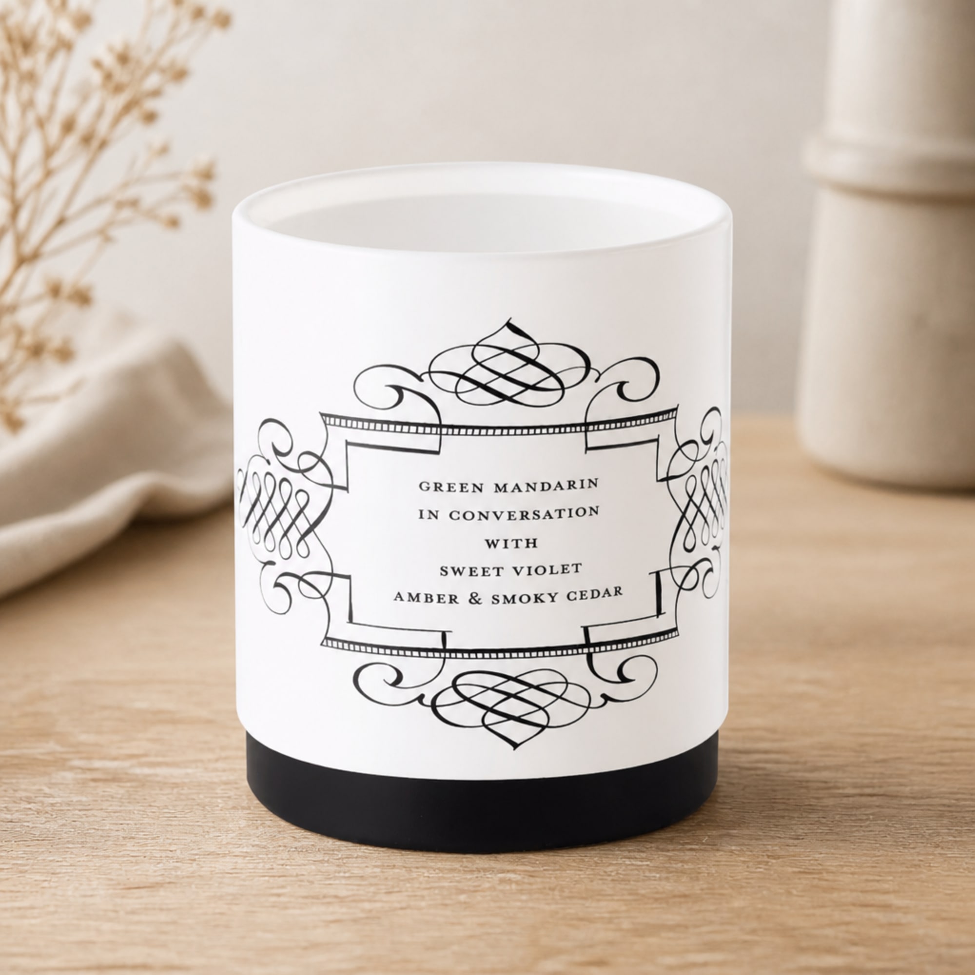 White candle in a black base with decorative label