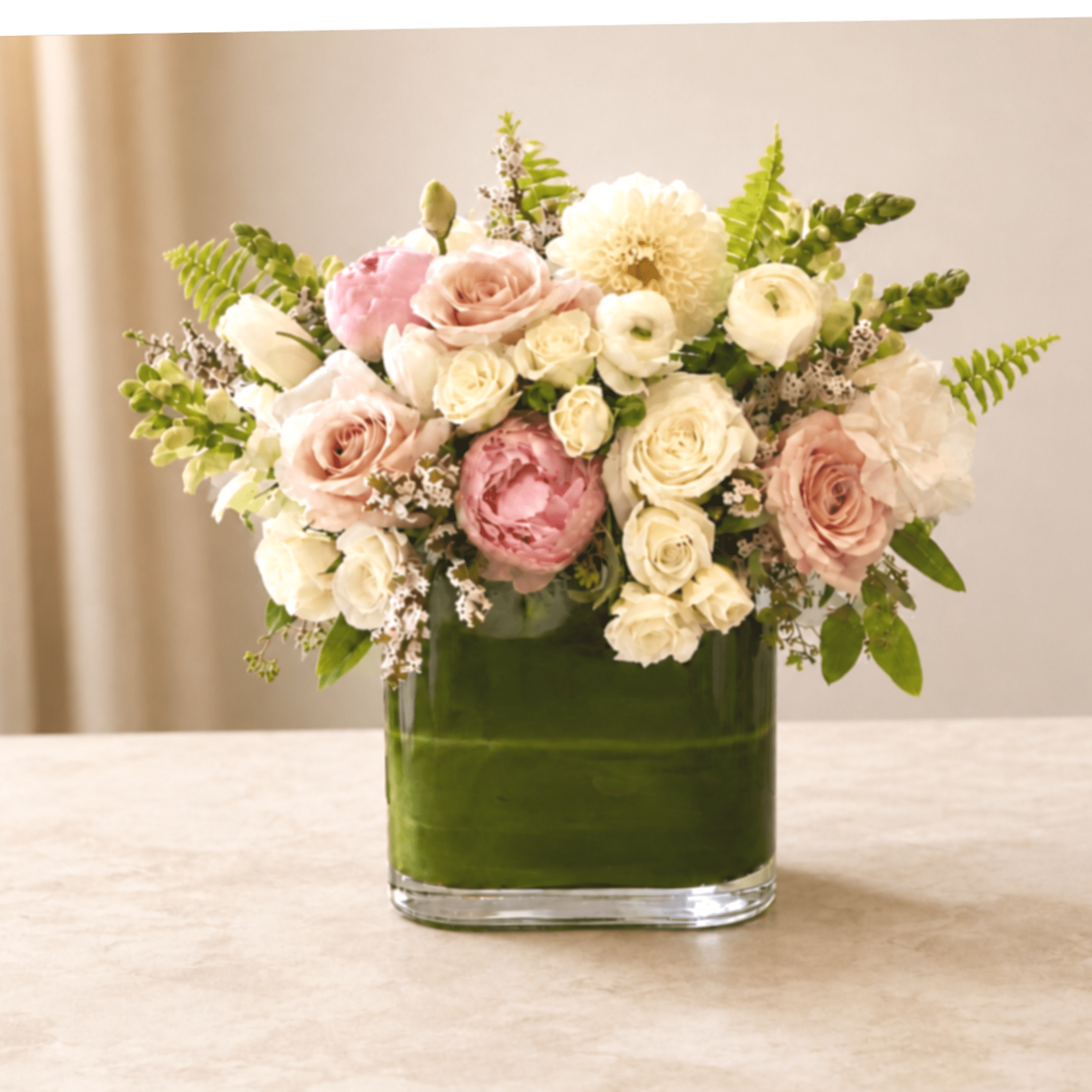Pink and white roses arranged in a green glass vase