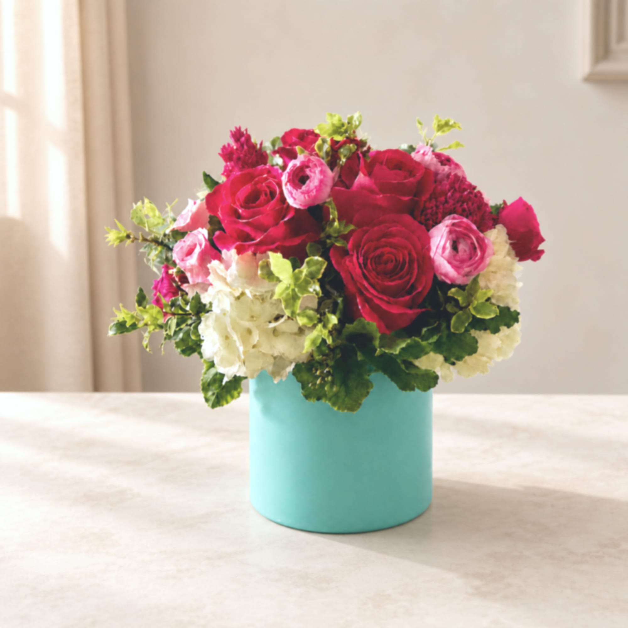 Pink and white flower arrangement in a turquoise box