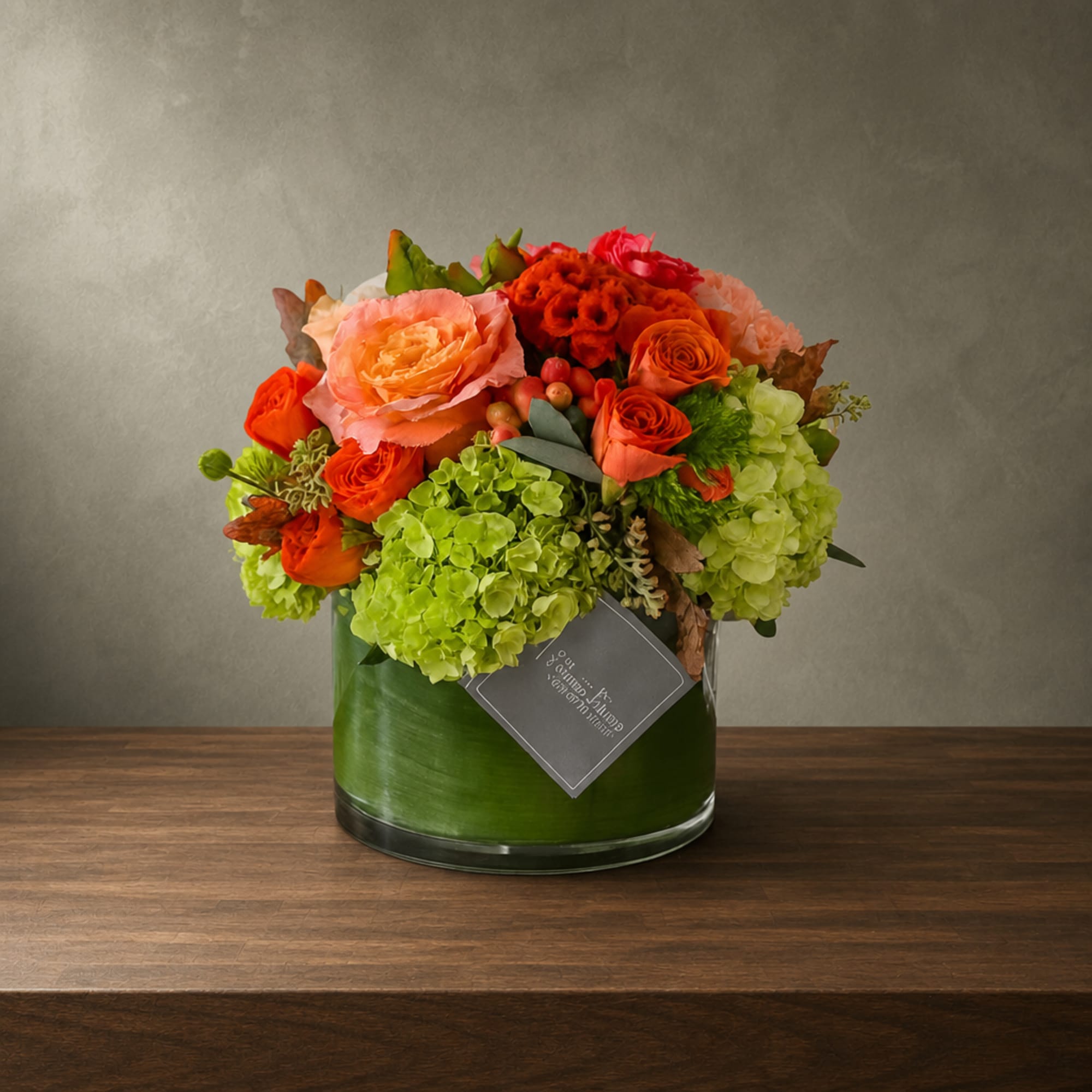 Mixed orange and peach flowers in a green glass vase