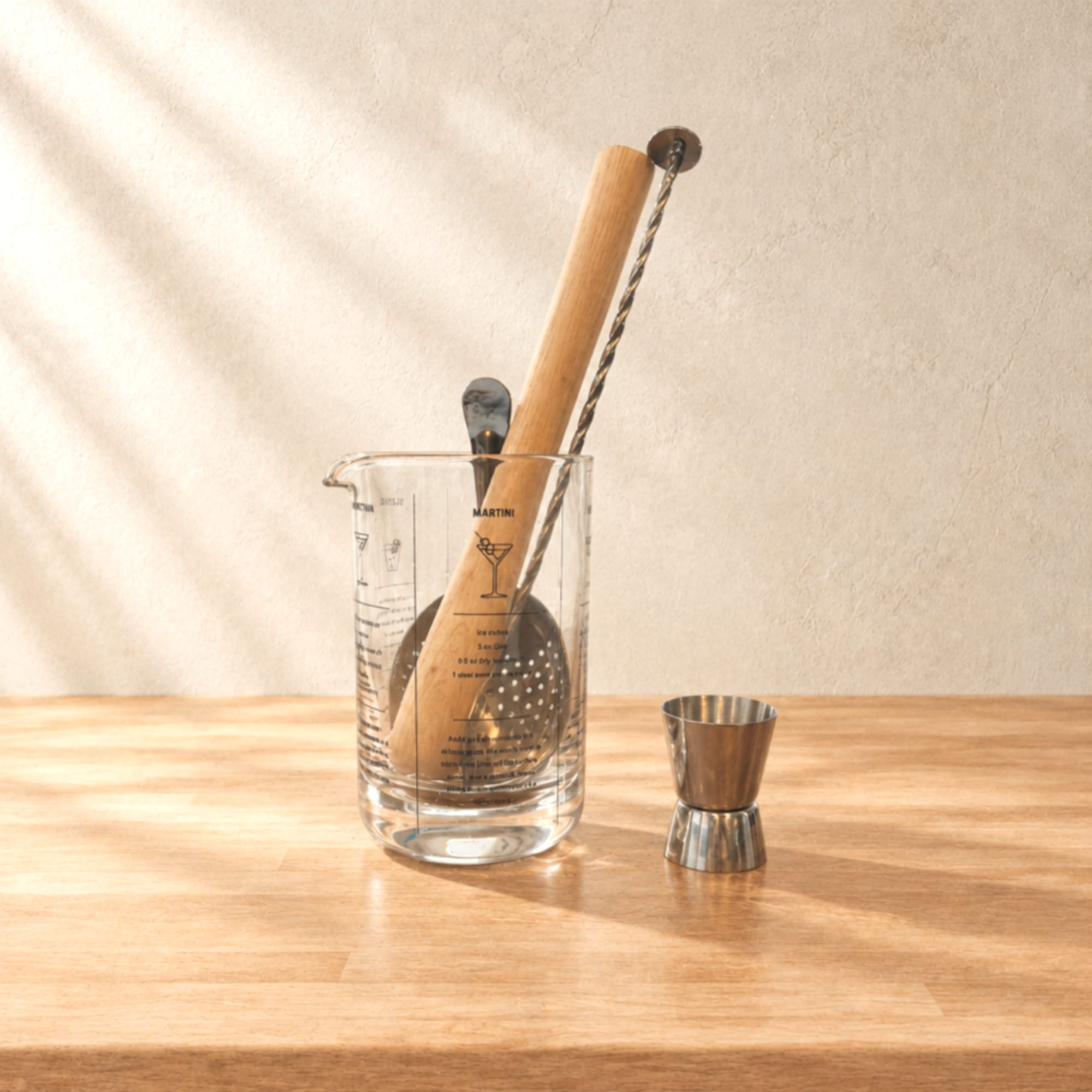 Cocktail mixing set with a glass beaker, wooden muddler, strainer, and jigger