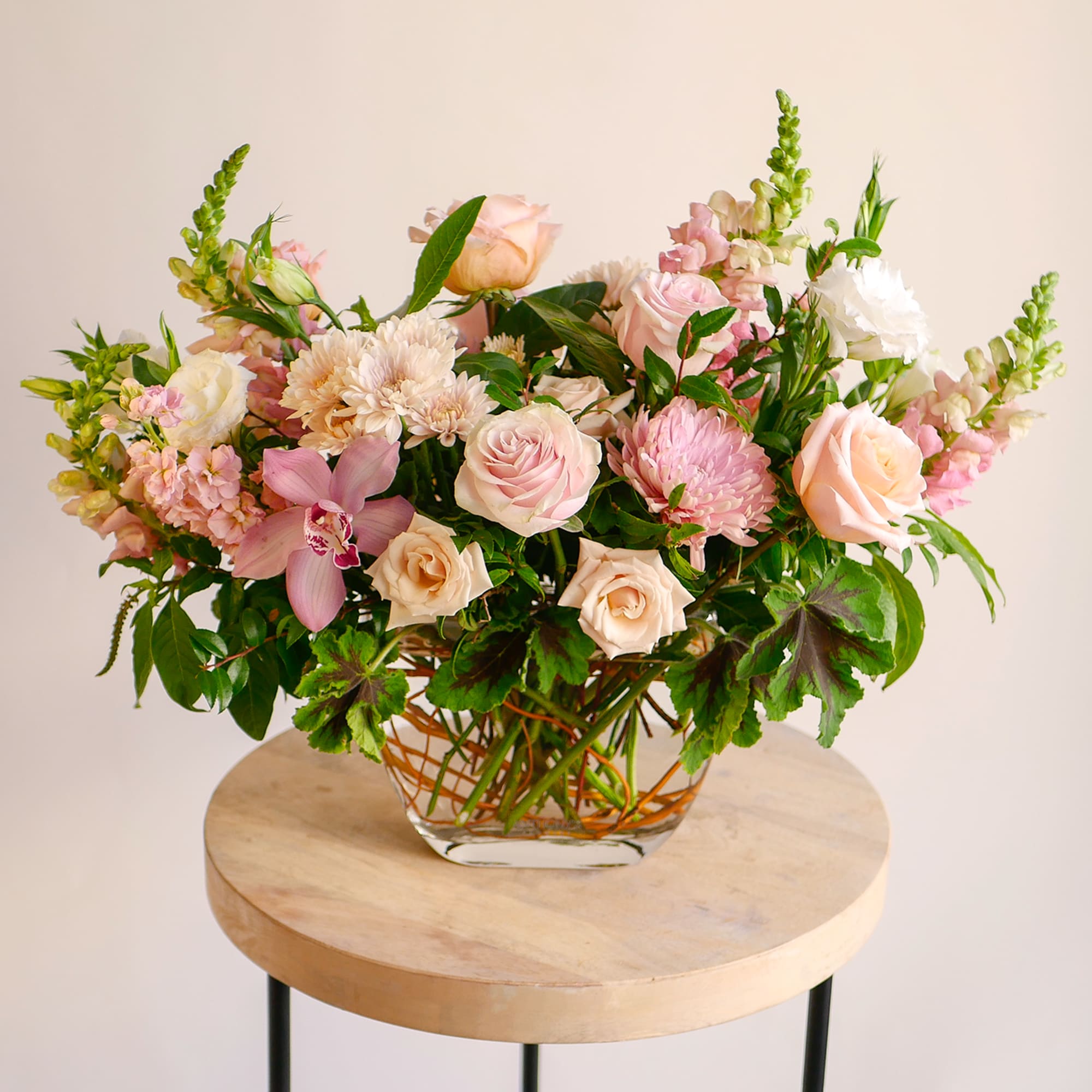 Pastel flower arrangement in a clear glass vase on a round table