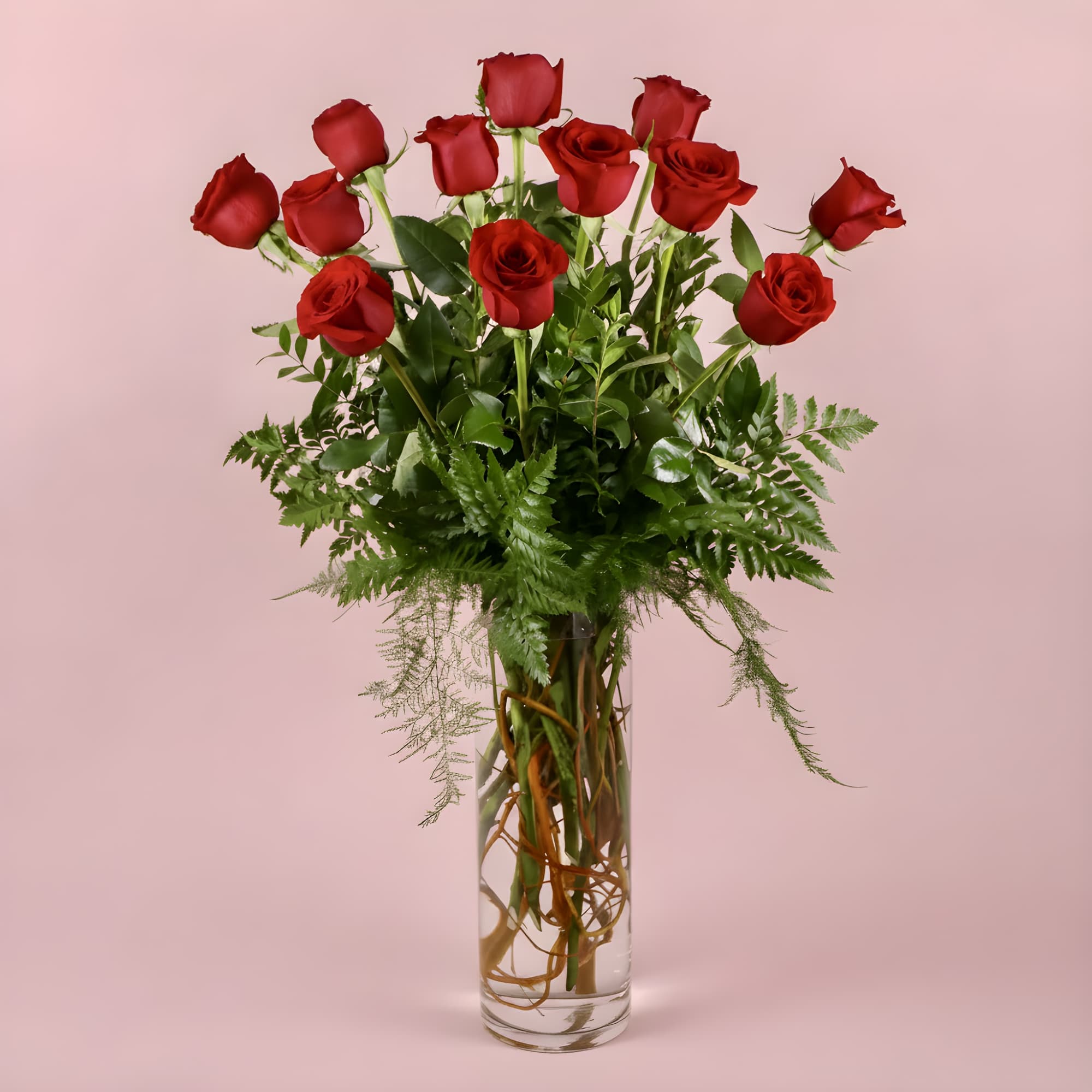 Red roses arranged in a tall clear glass vase