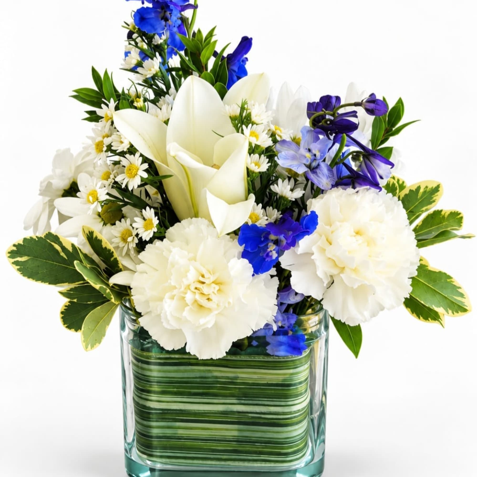 White lilies, carnations, and blue flowers in a square glass vase