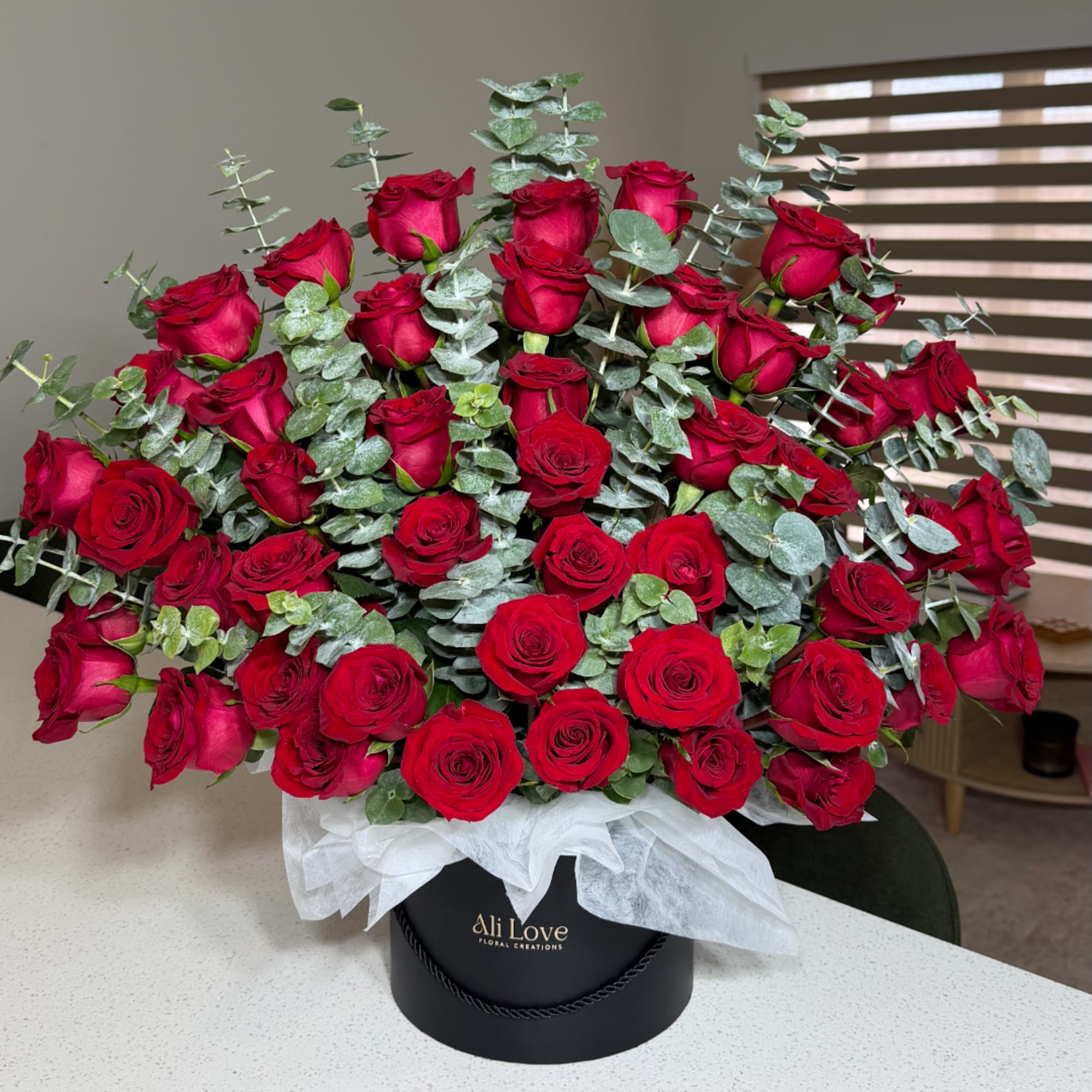 Large bouquet of red roses with eucalyptus in a black hat box