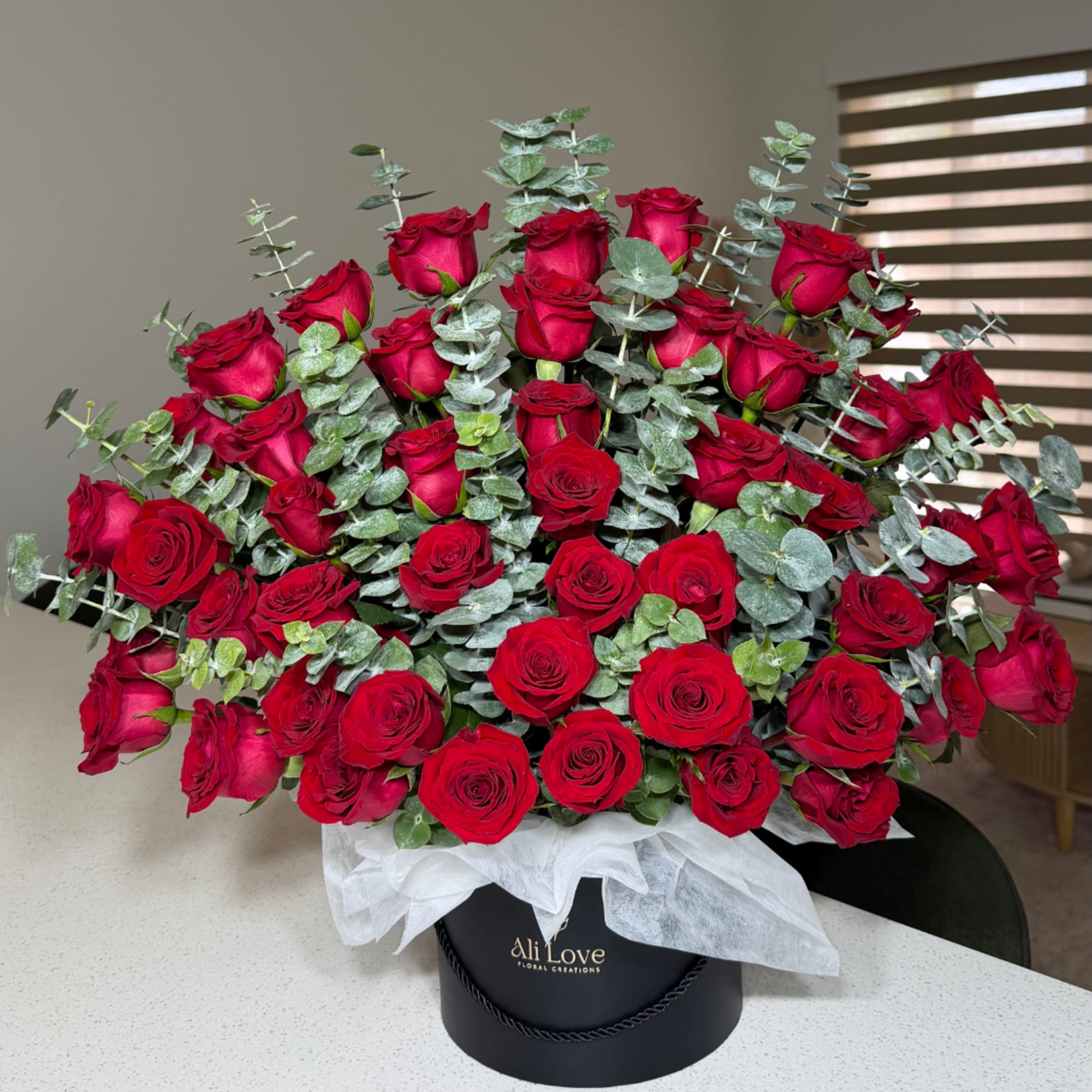 Large bouquet of red roses with eucalyptus in a black hatbox