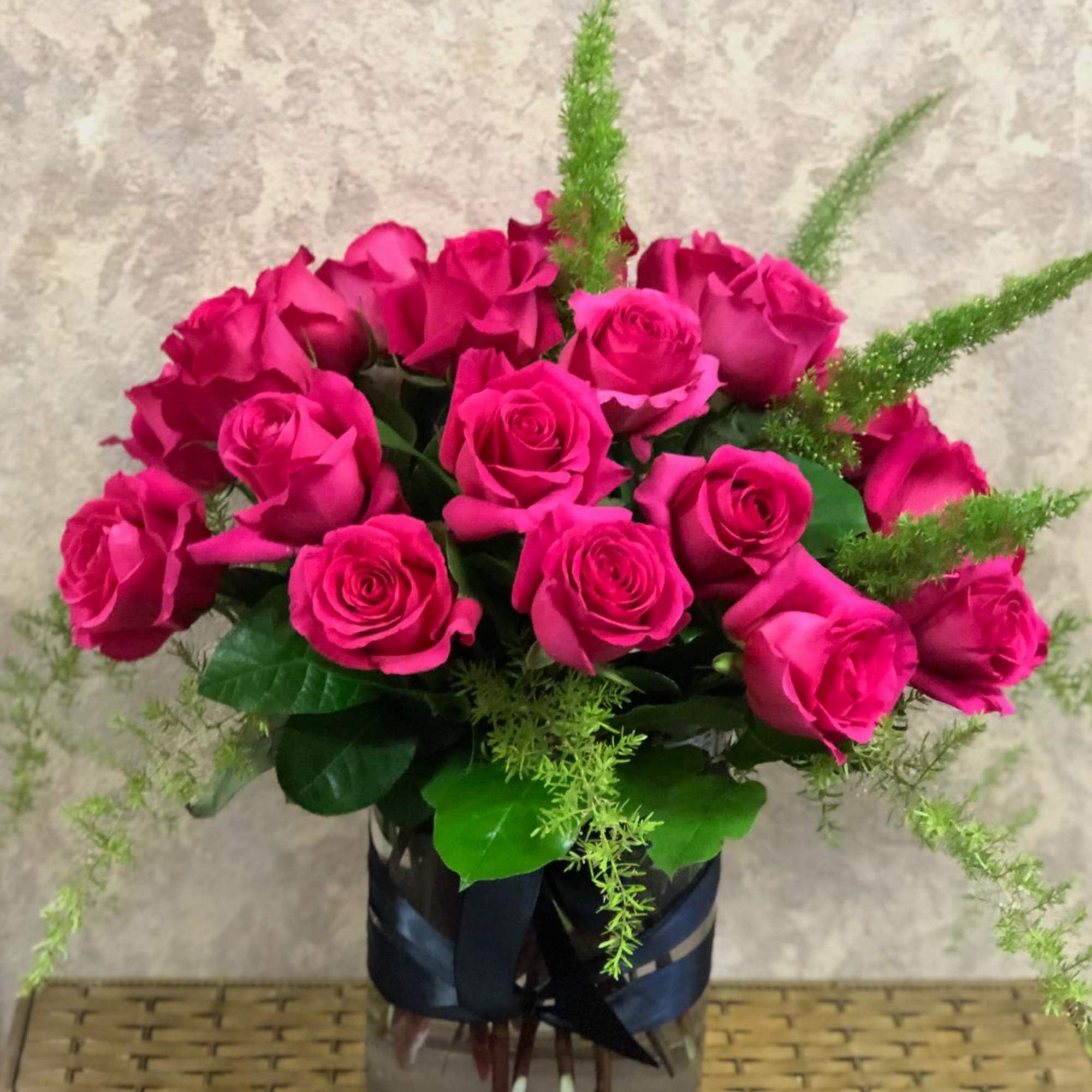 Pink roses arranged in a glass vase with green filler
