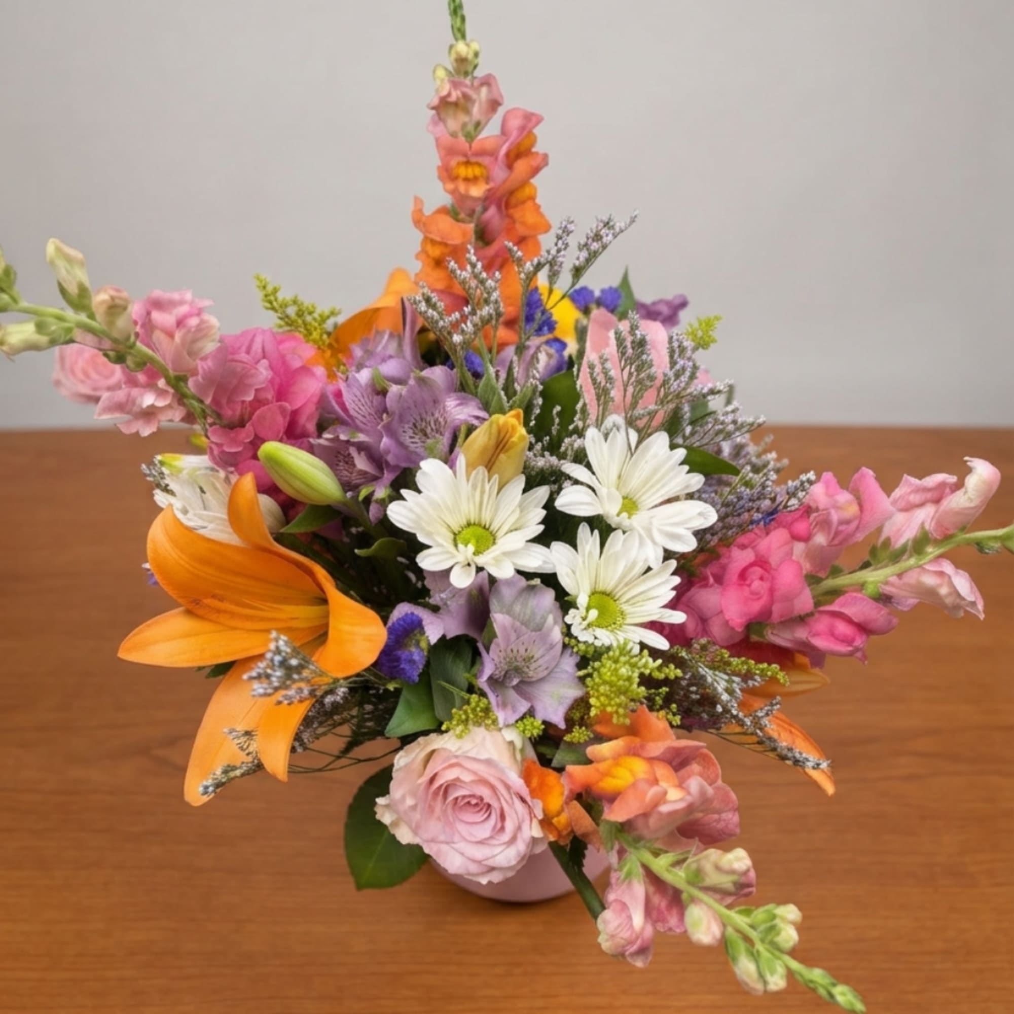 Colorful mixed bouquet with lilies, daisies, roses, and snapdragons in a vase