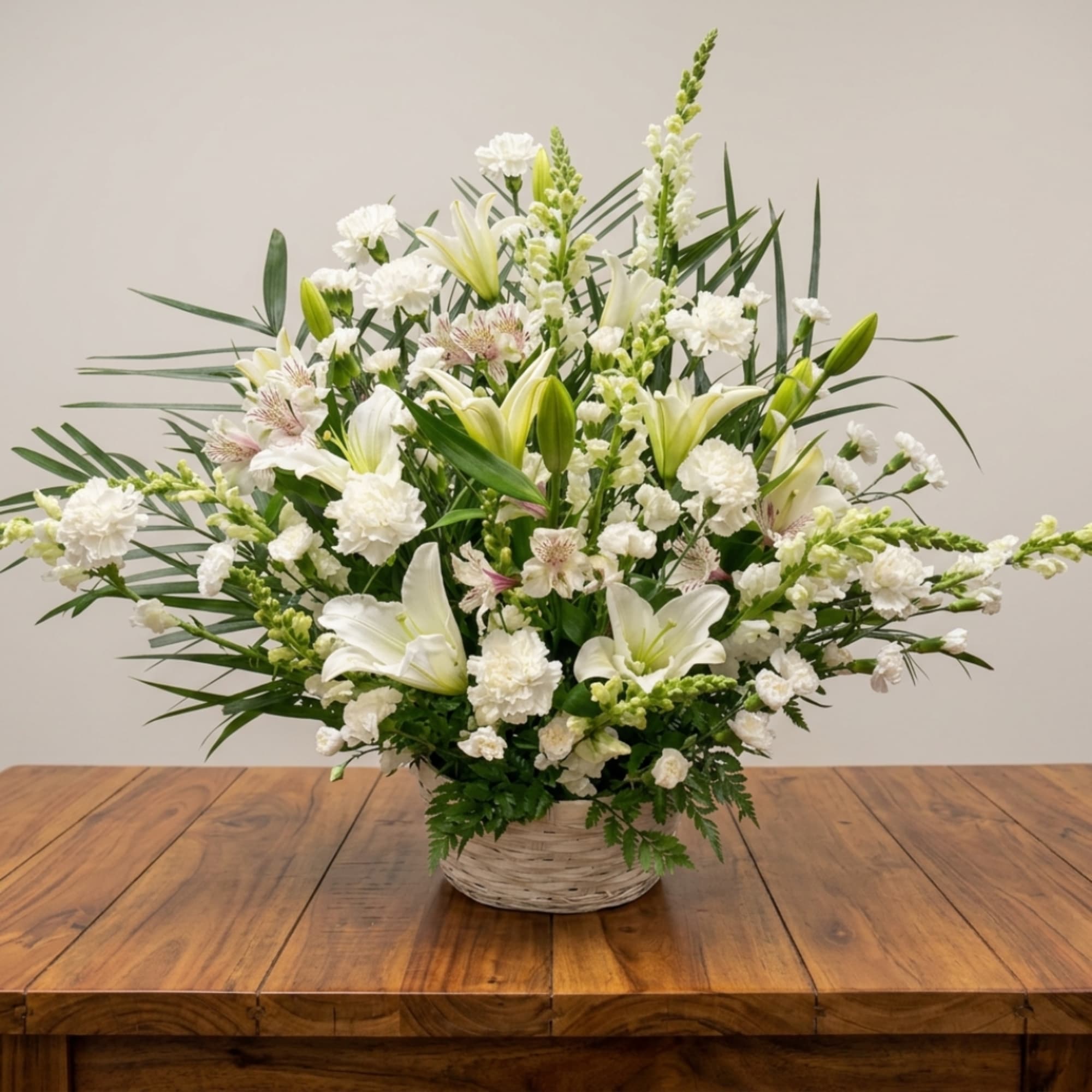 White lilies and carnations arranged in a wicker basket