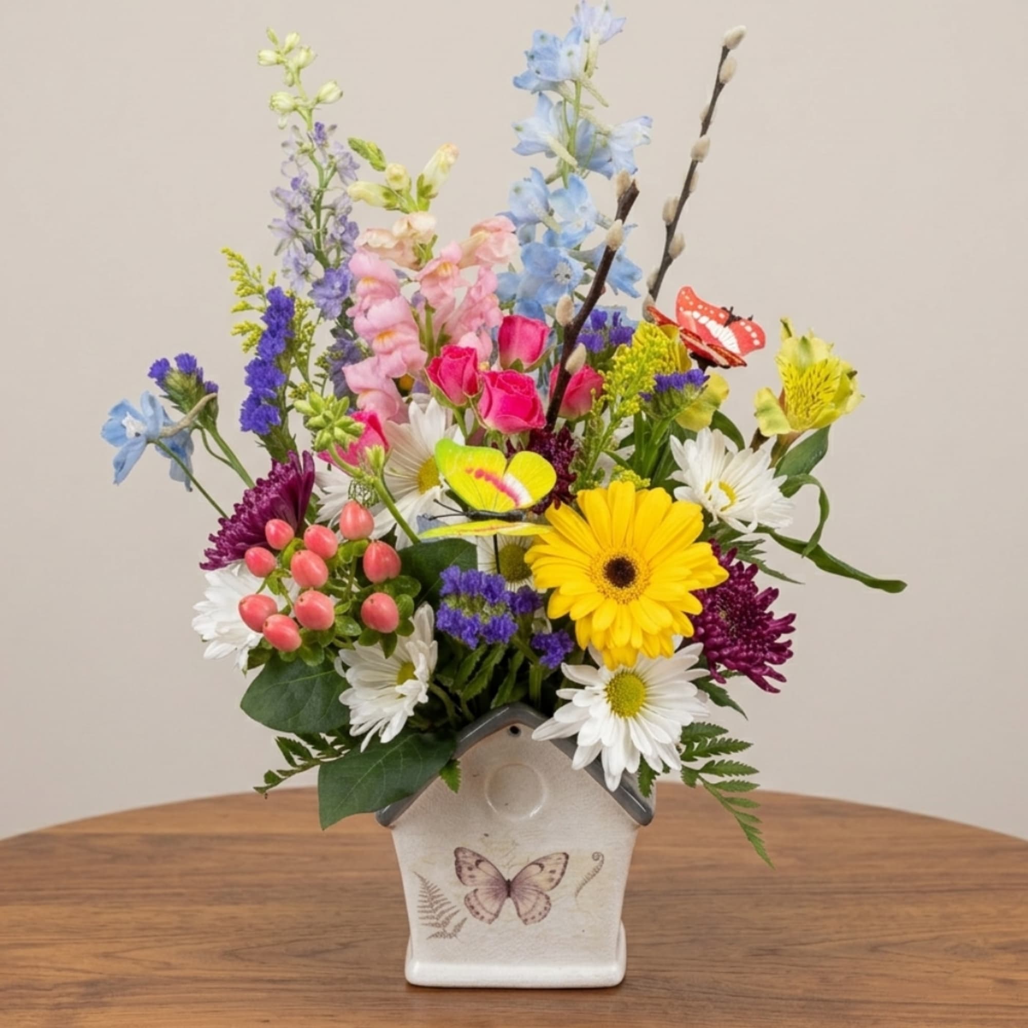 Colorful mixed flower arrangement in a butterfly-decorated ceramic vase