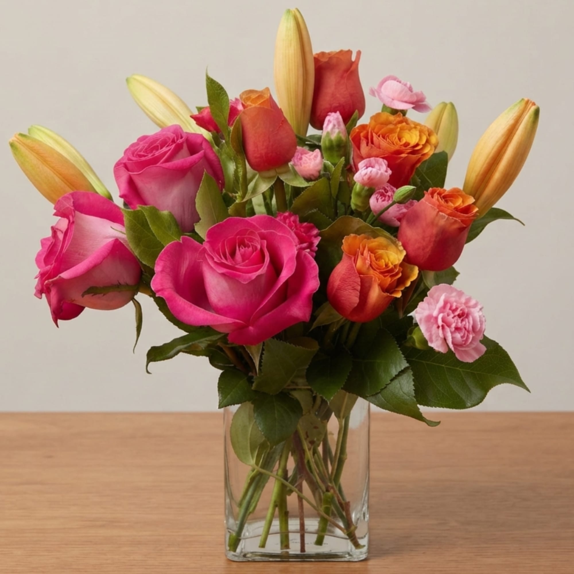 Pink and orange rose bouquet with lilies in a clear glass vase