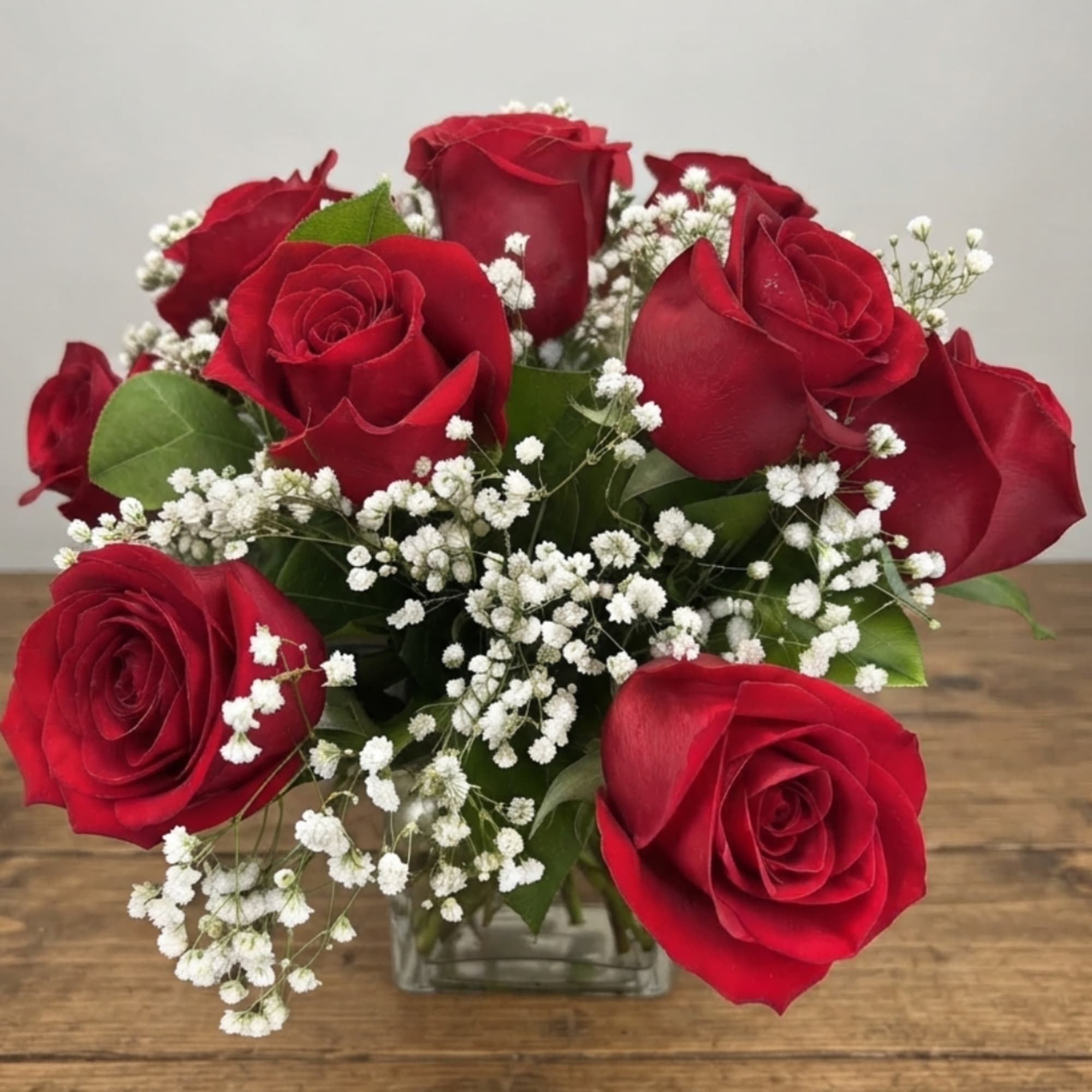Bouquet of red roses and white baby's breath in a clear glass vase