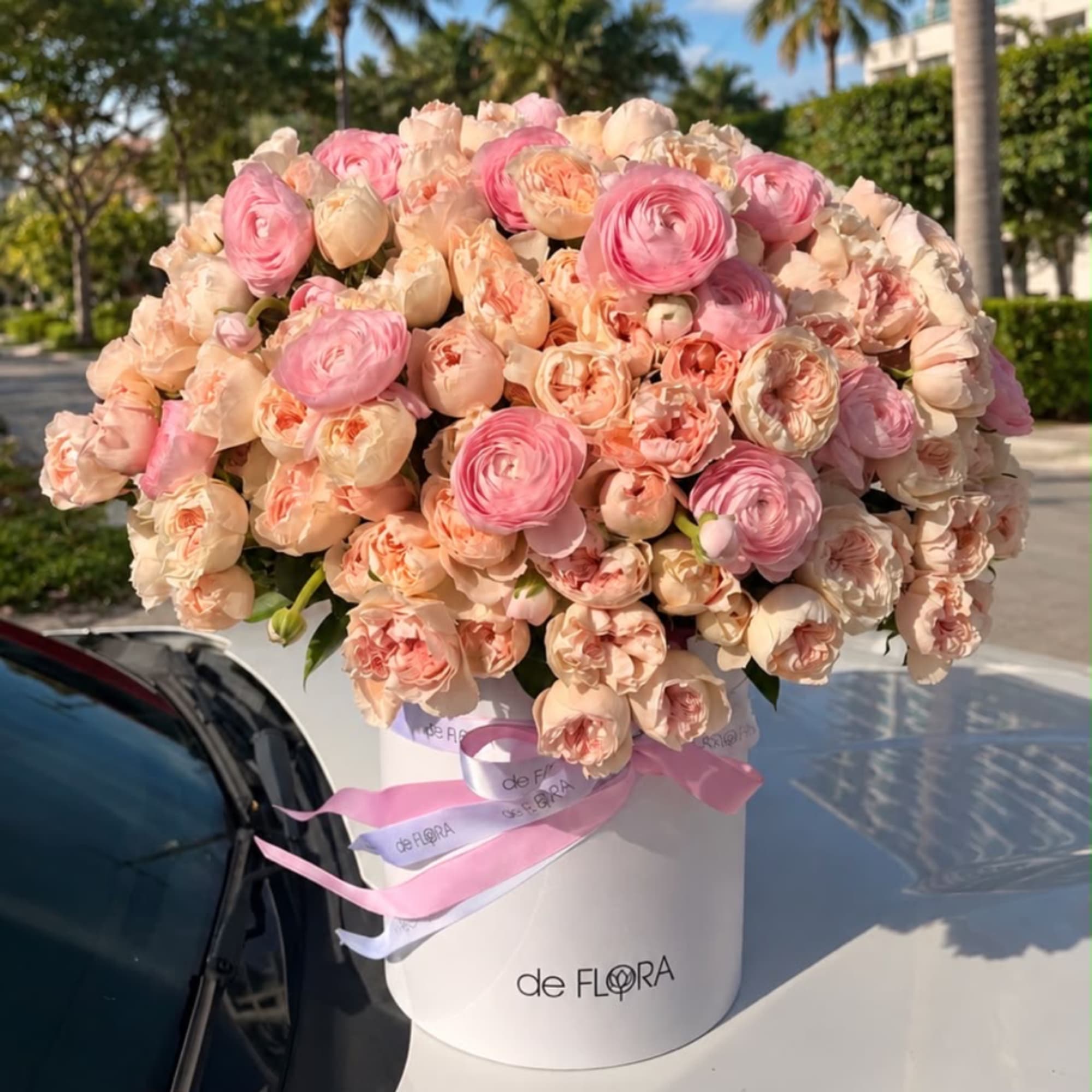 Large pink and peach flower arrangement in a white hat box with ribbon