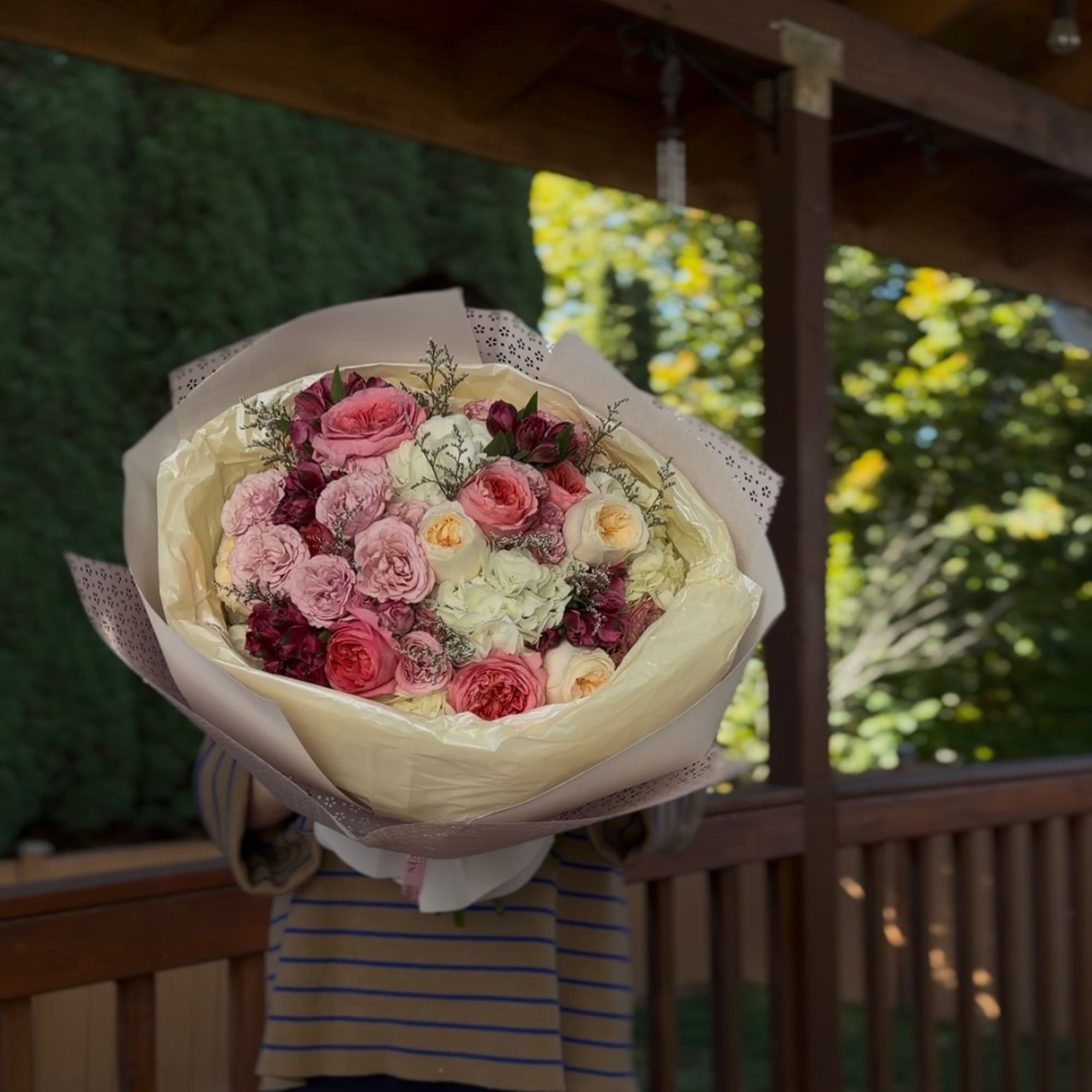 Large bouquet of pink and white roses wrapped in cream paper