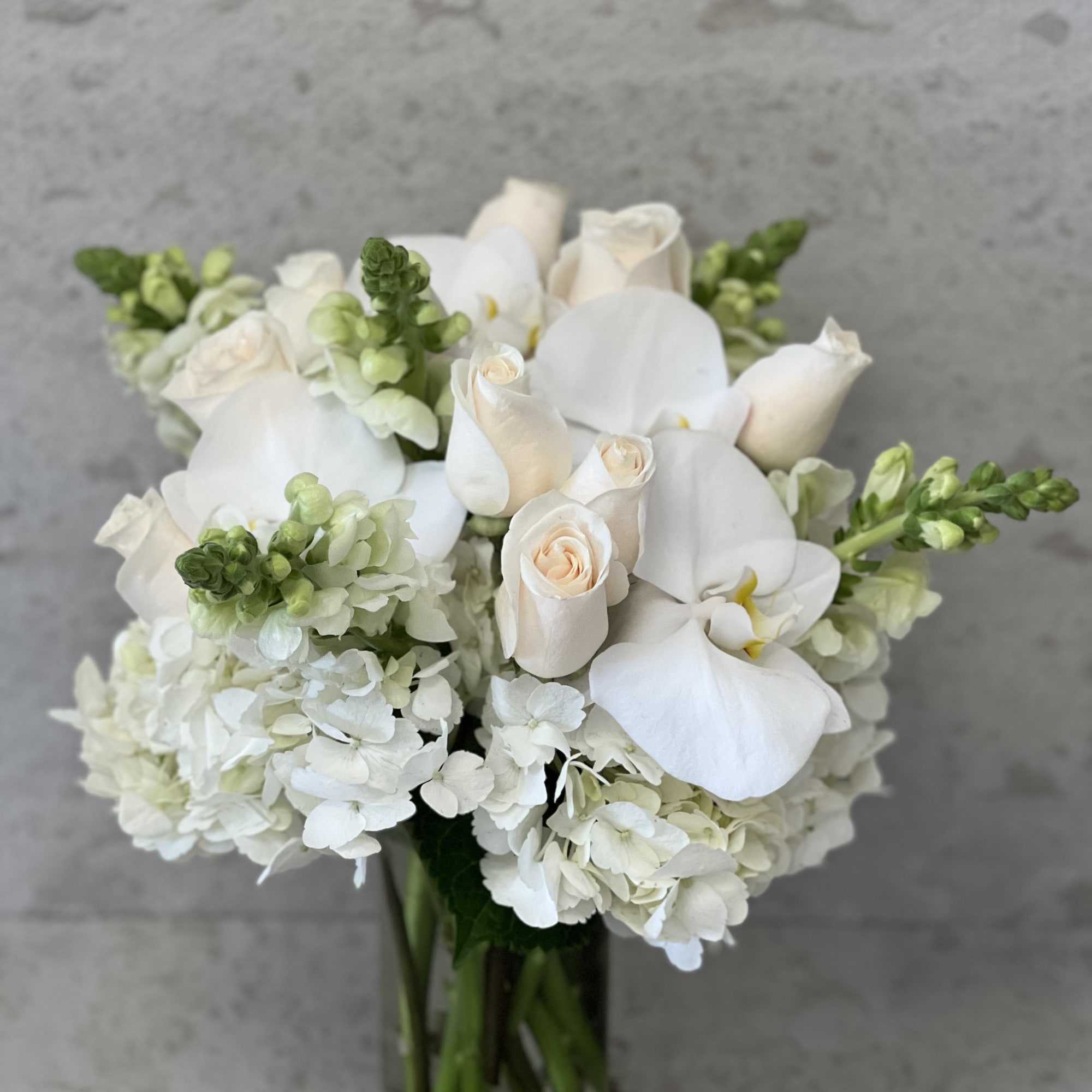 White roses and orchids arranged in a glass vase