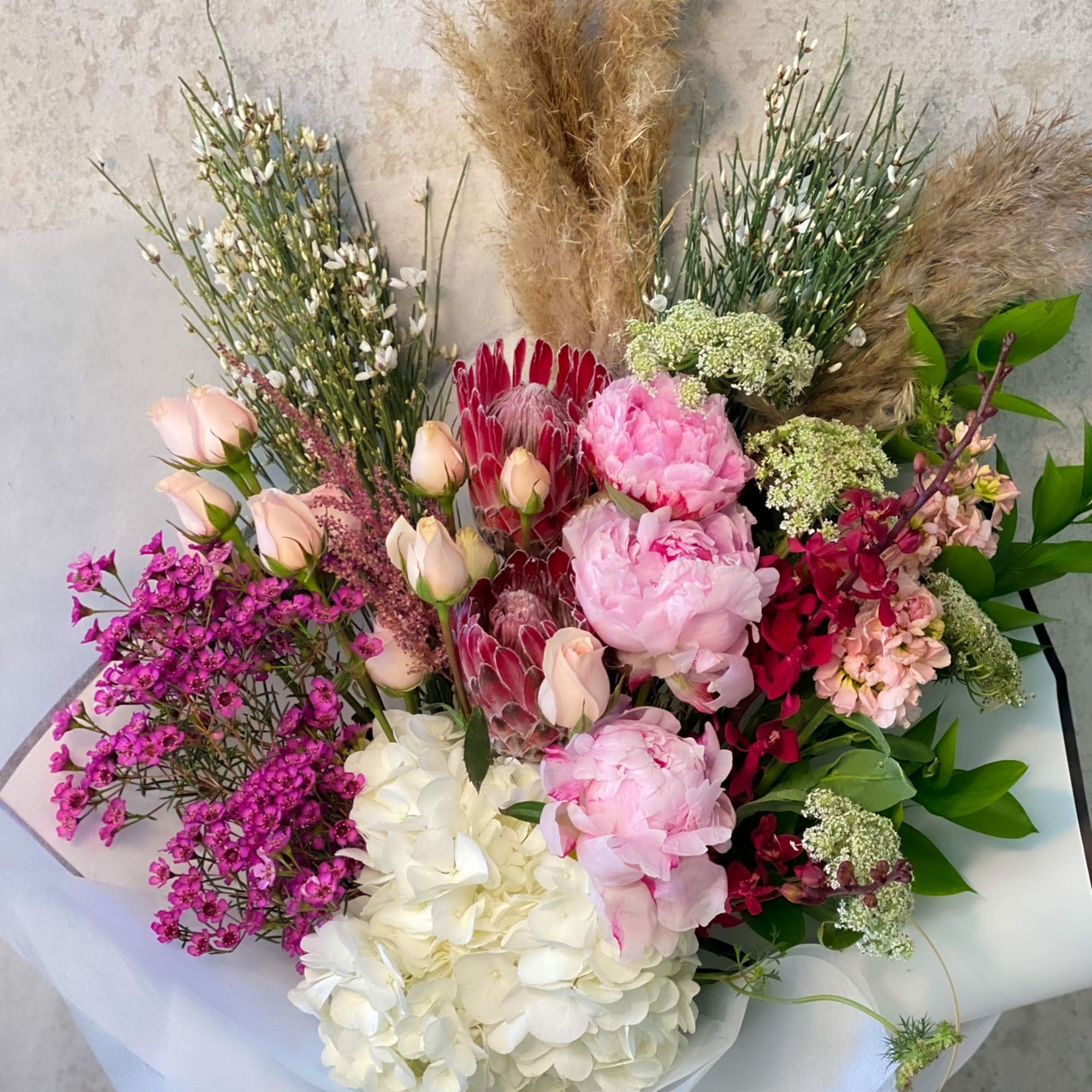 Mixed bouquet with pink peonies, white hydrangea, and red protea