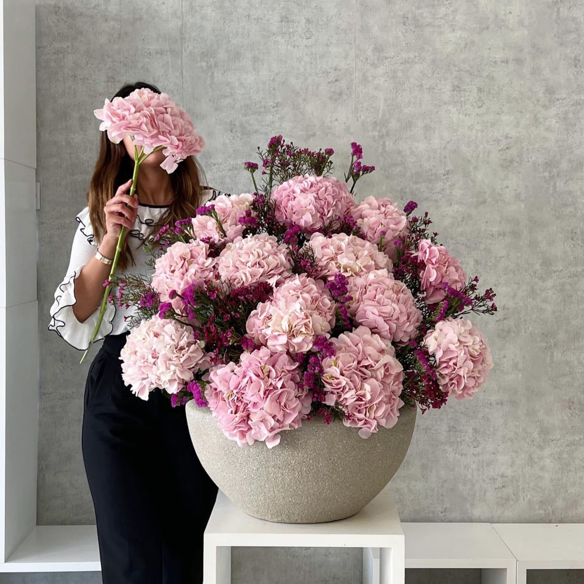 Large pink hydrangea arrangement in a textured bowl vase