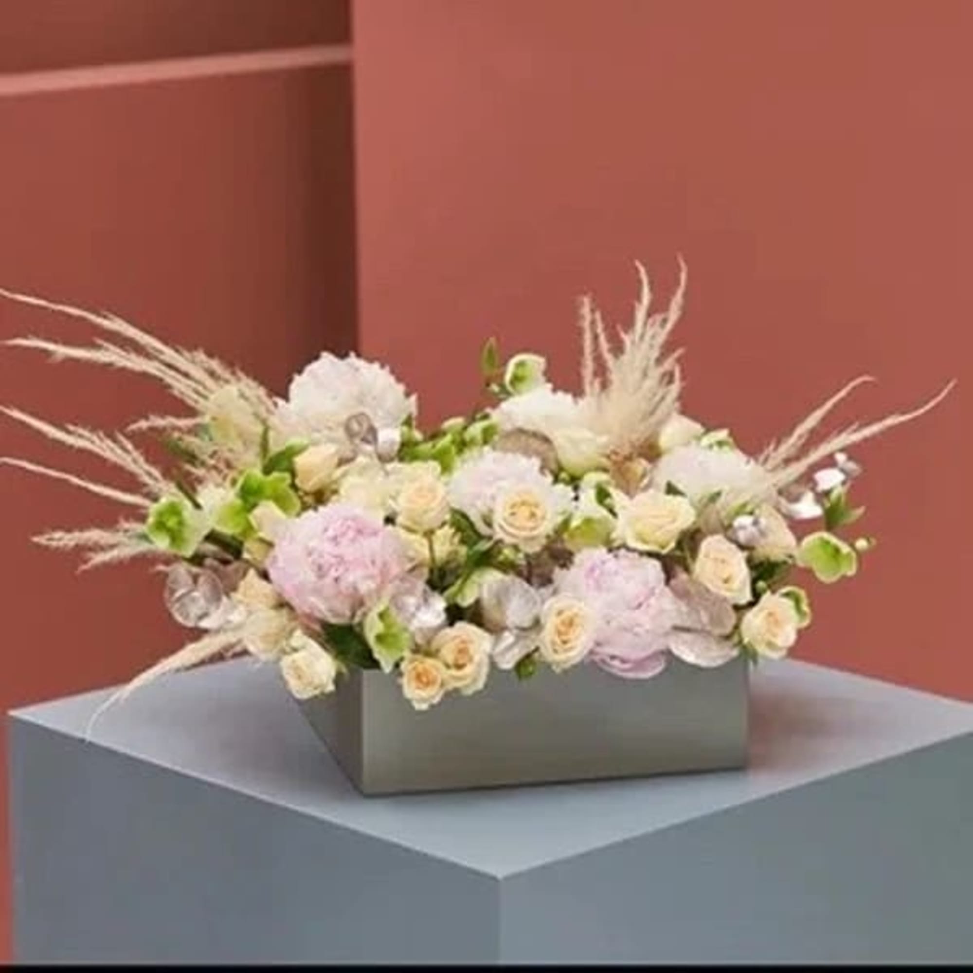 Low floral arrangement in a rectangular box with pale pink and white blooms
