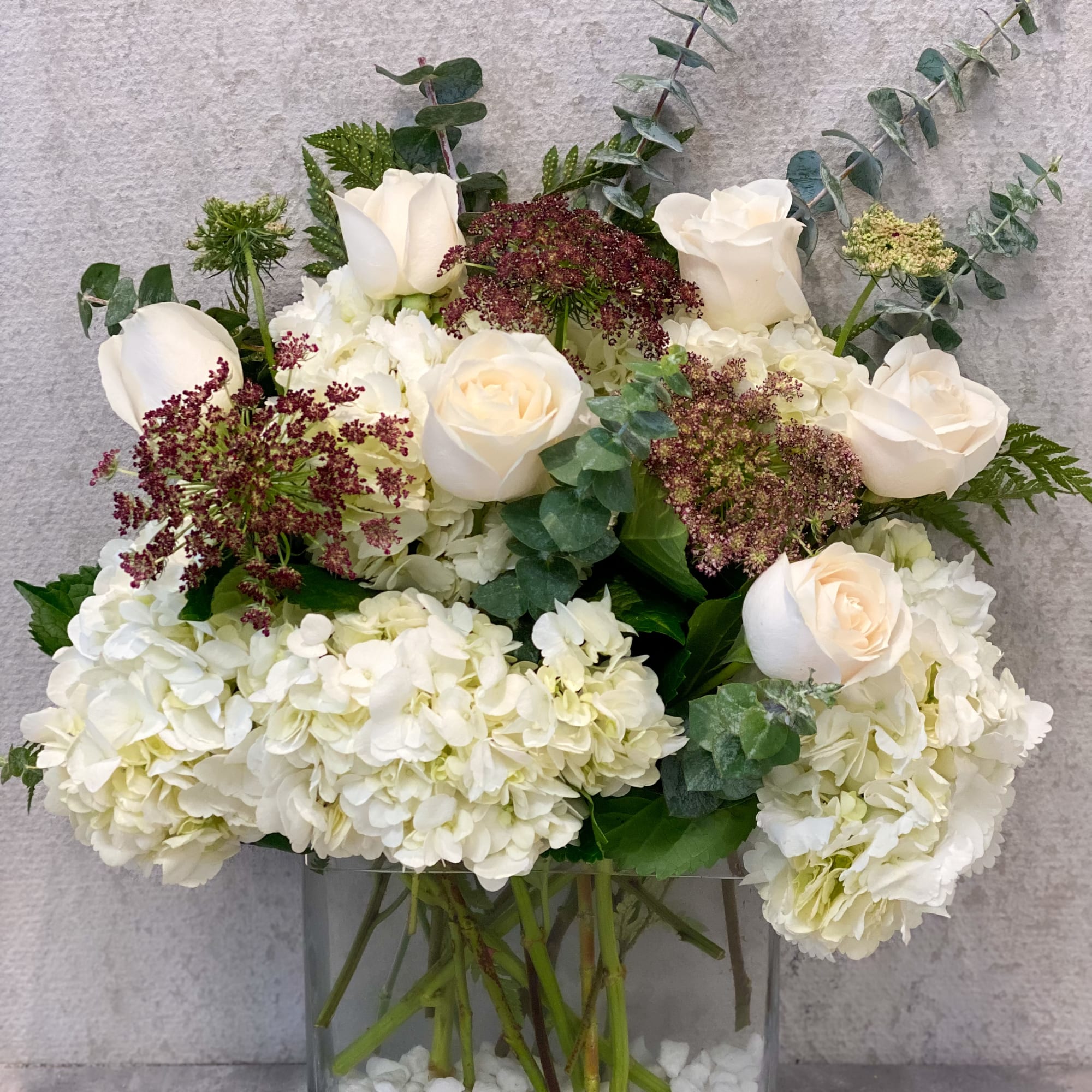 White roses and hydrangeas arranged in a glass vase